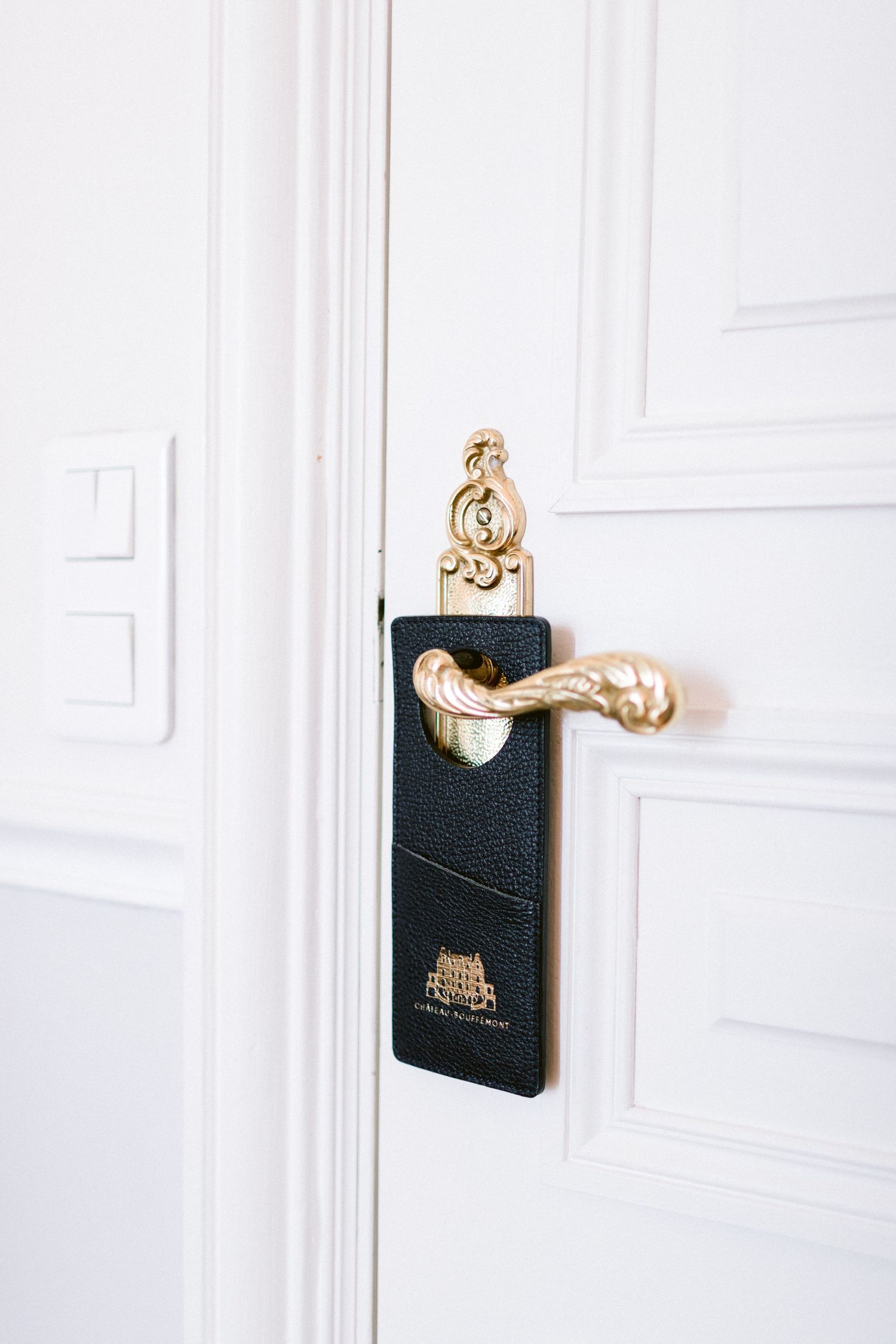 Elegant gold door handle and black key card holder mounted on a white door.