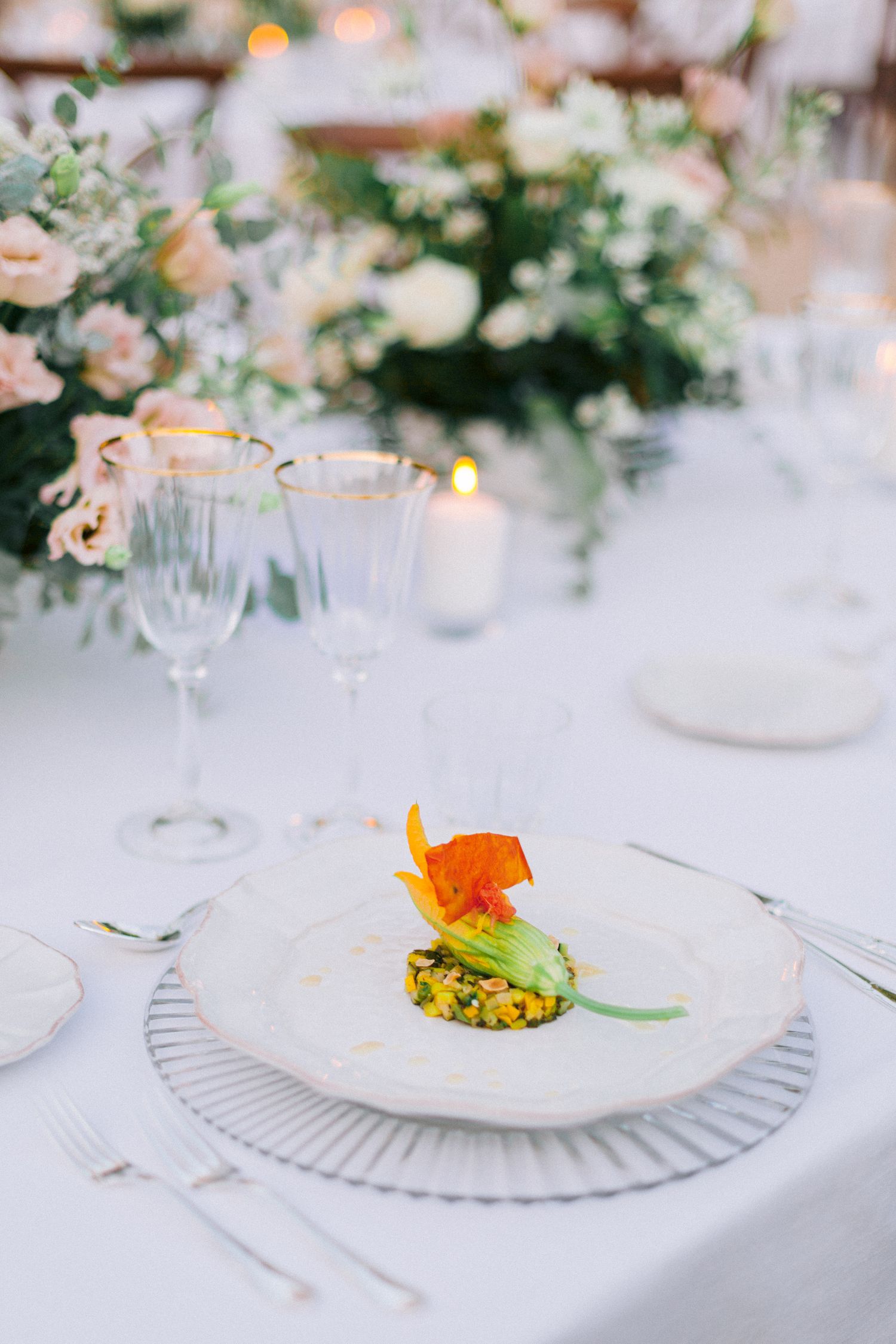 Elegant white place settings with delicate floral centerpieces and fine china plates on a formal dining table.