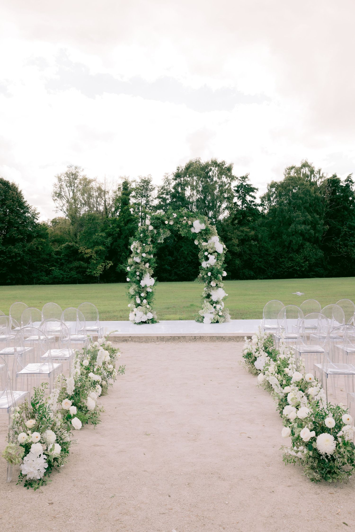 Elegant outdoor wedding ceremony space at Château de Sept Saulx with white chairs and floral aisle decorations.