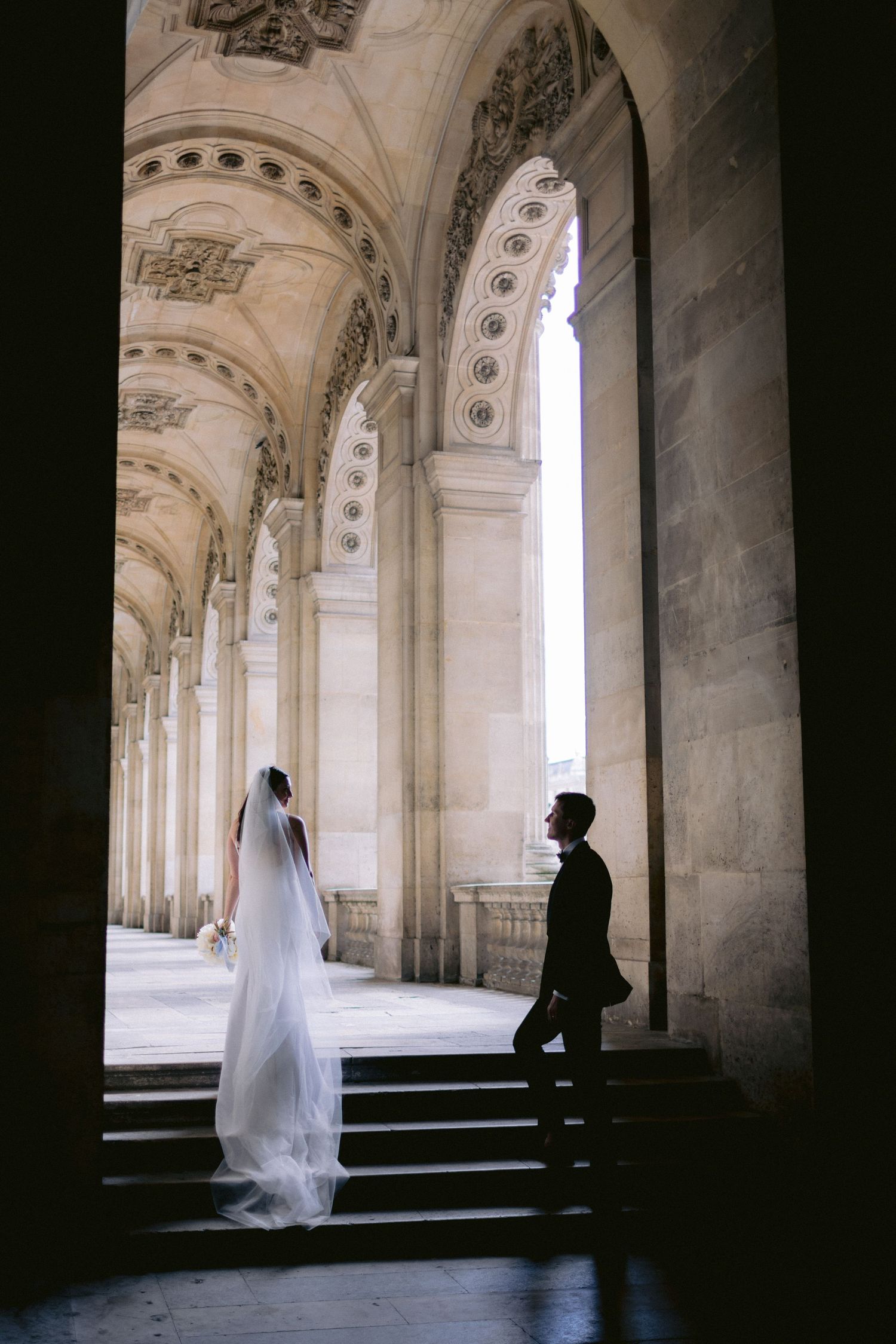 Artistic black and white wedding photos captured under stone archways with dramatic lighting and shadows.