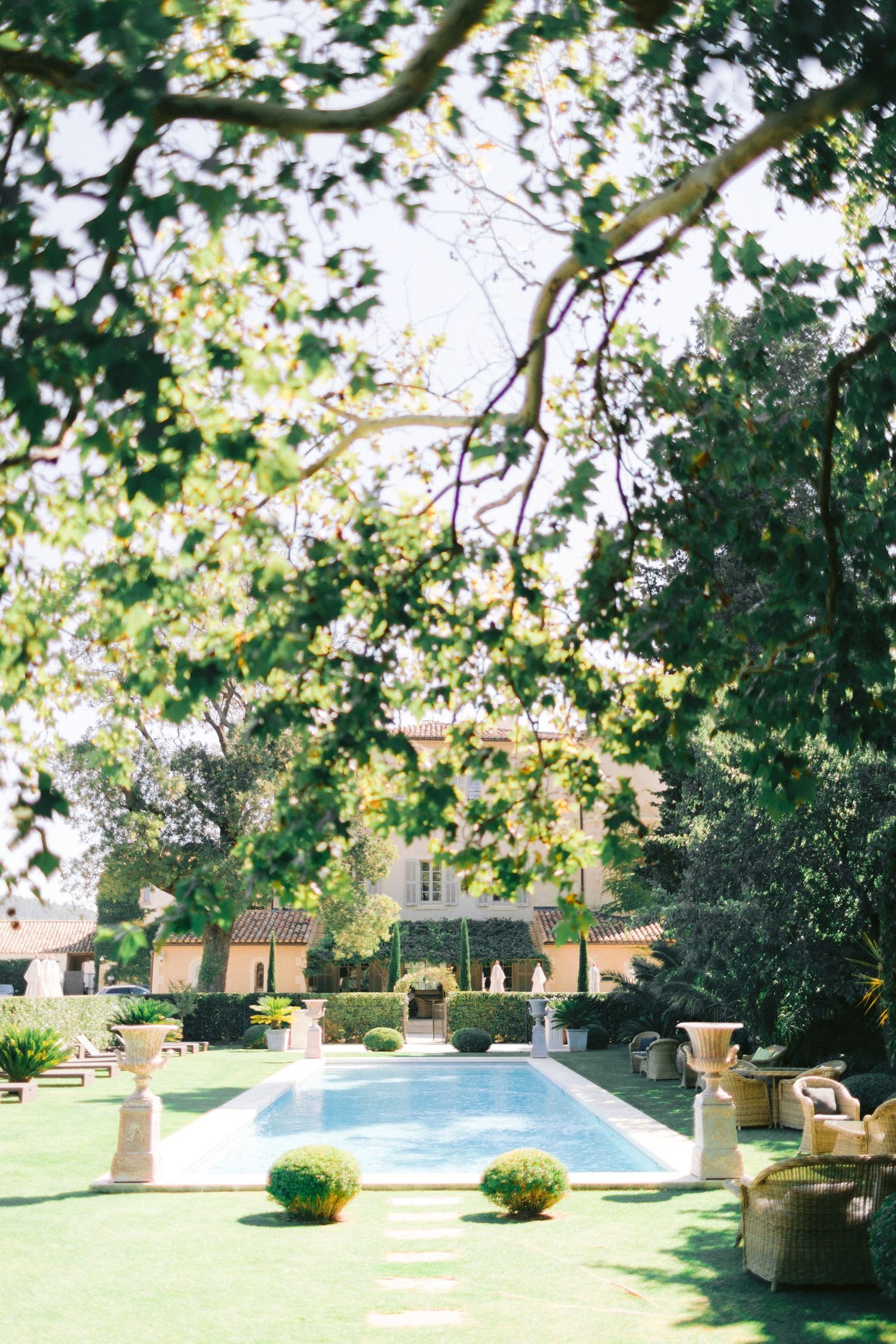 Lush garden setting with swimming pool and manicured lawn surrounded by trees.