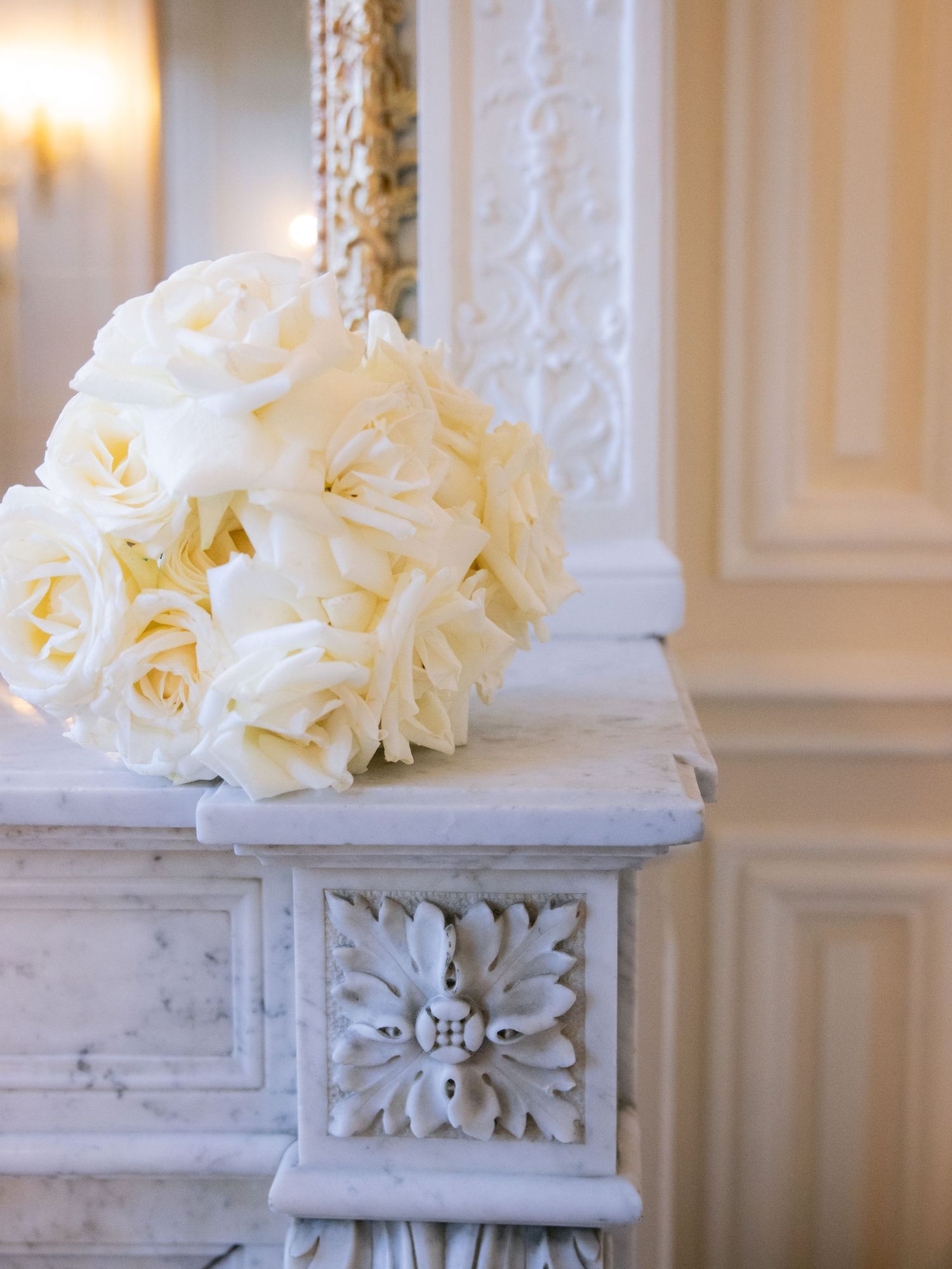 White floral decorations adorn an ornate marble pedestal with carved details.