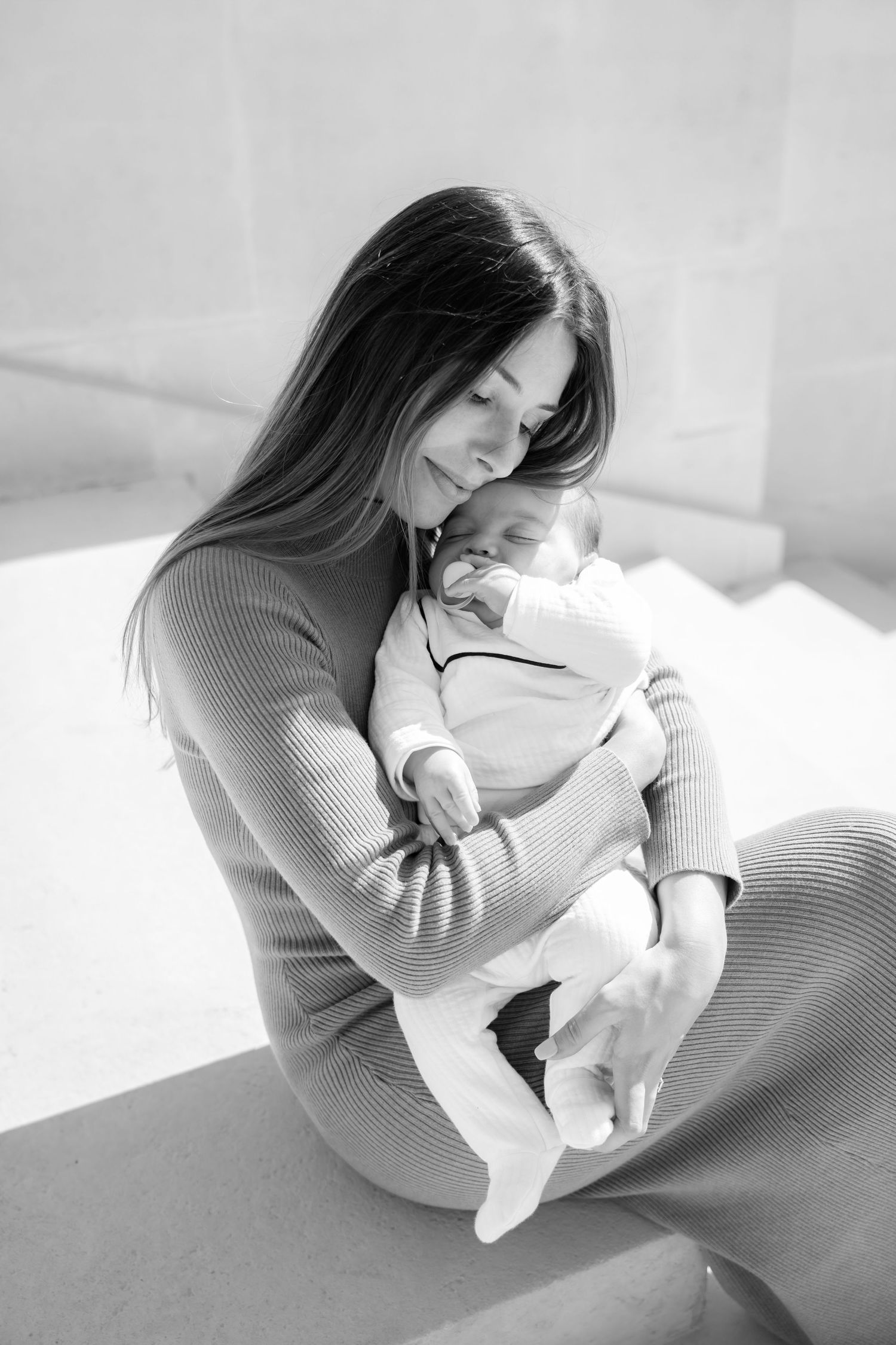 Black and white intimate photos showing tender moments with a newborn baby in a cozy indoor setting.