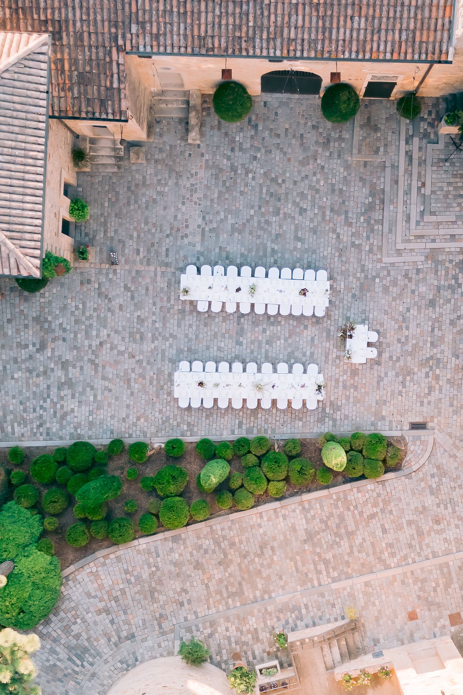 Aerial view of outdoor wedding venue with white chairs arranged in rows on stone patio.