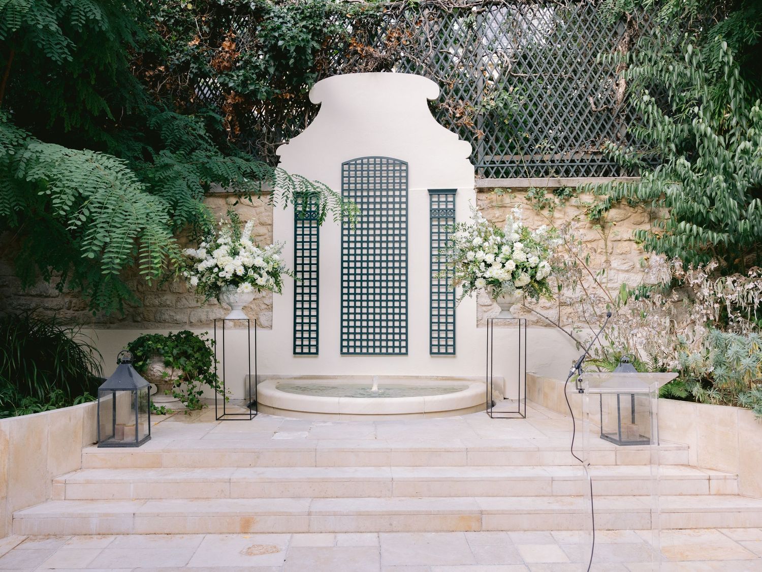 White stone steps and lattice panels decorated with floral arrangements for an outdoor wedding ceremony.