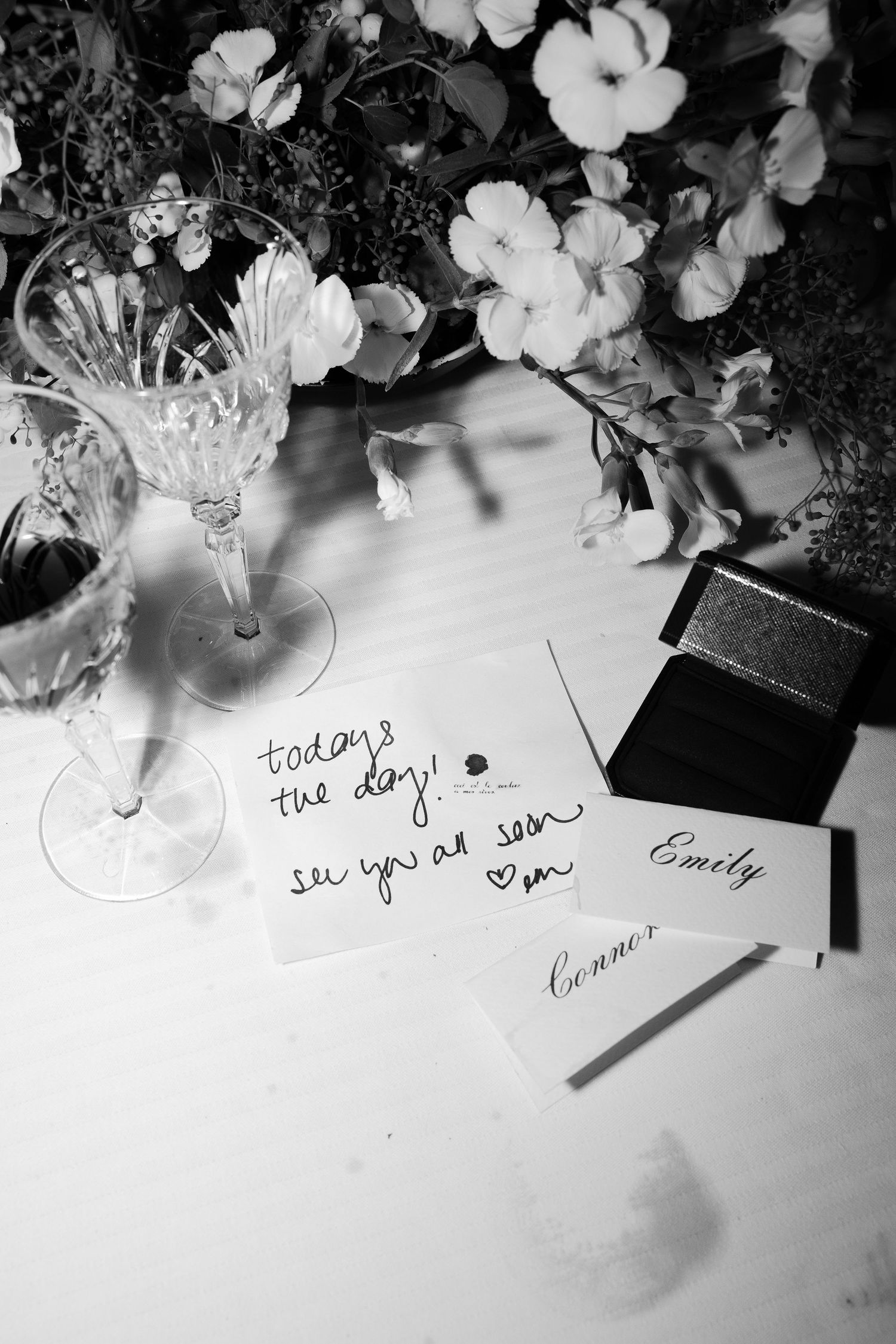 A series of handwritten notes displayed with white flowers and glass vases in black and white photography.