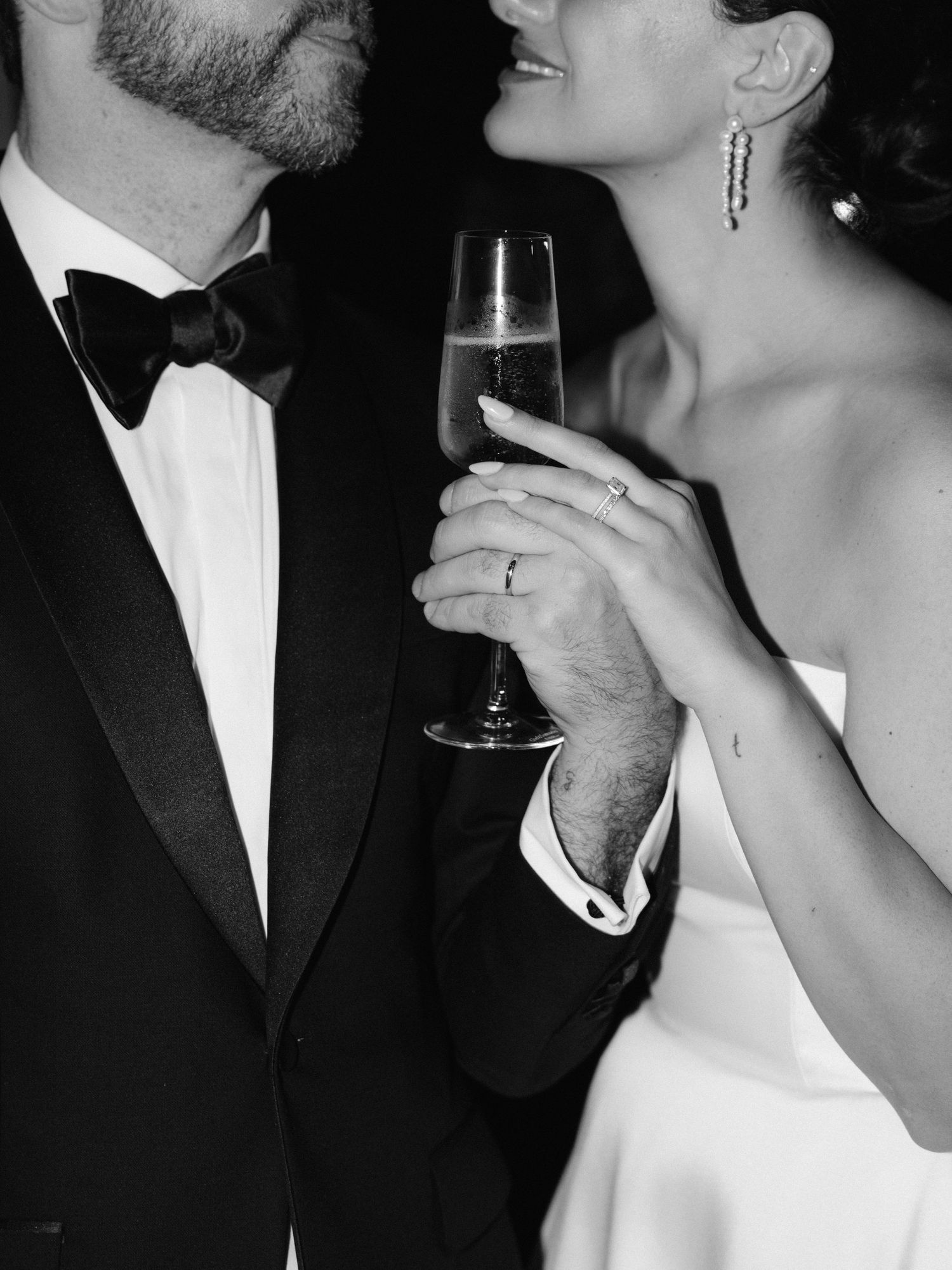 Intimate black and white portraits of a couple sharing champagne in formal wedding attire.