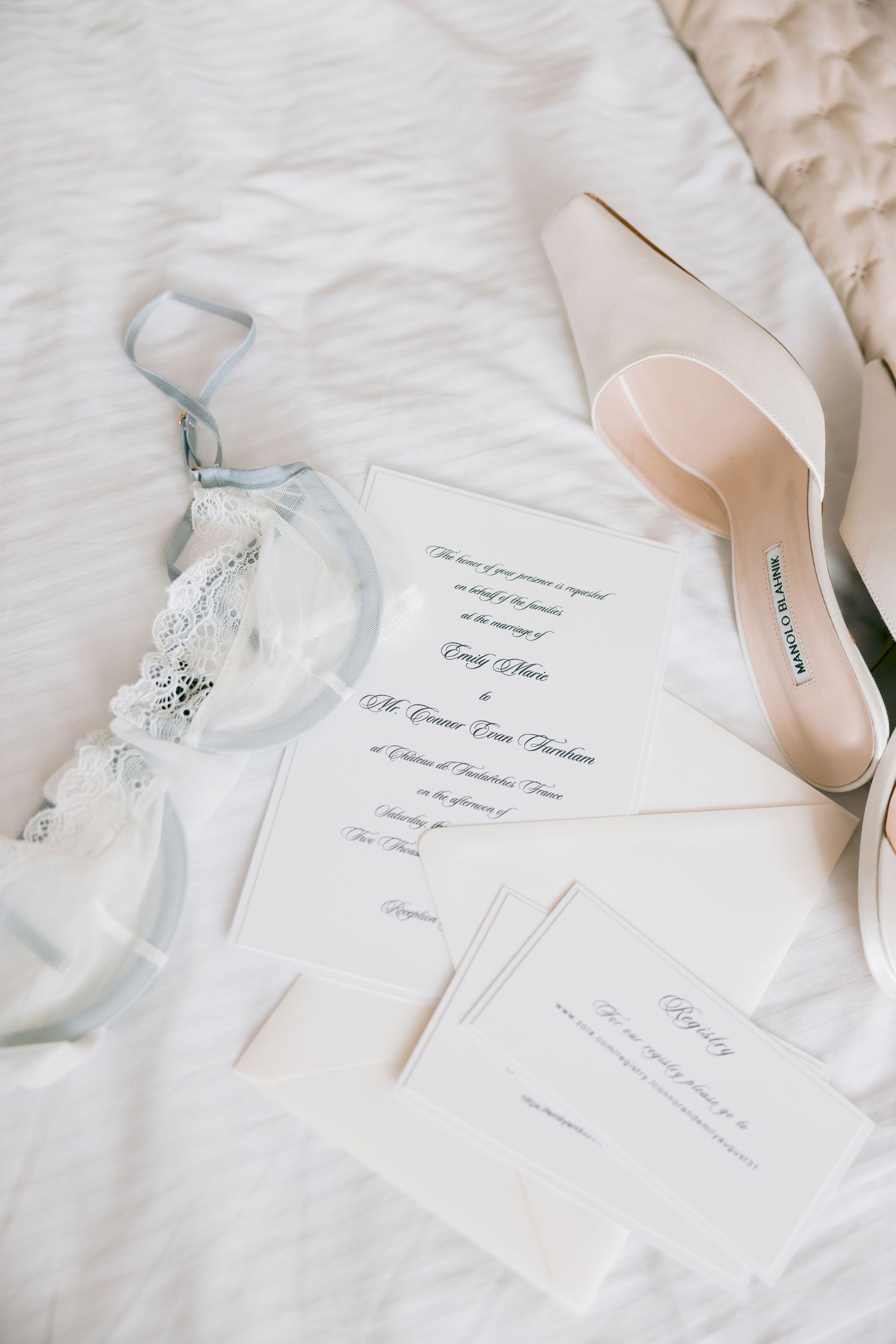 Wedding invitation and delicate bridal accessories arranged on white linens.