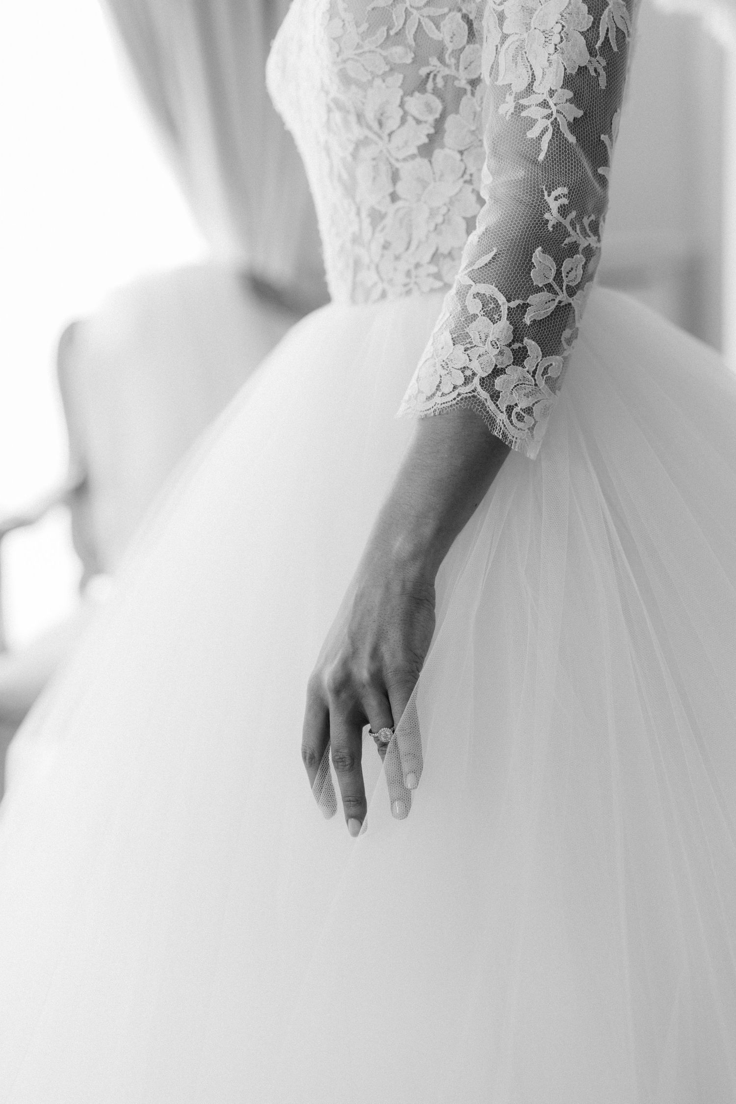 Close-up details of delicate lace and tulle on a white wedding gown.