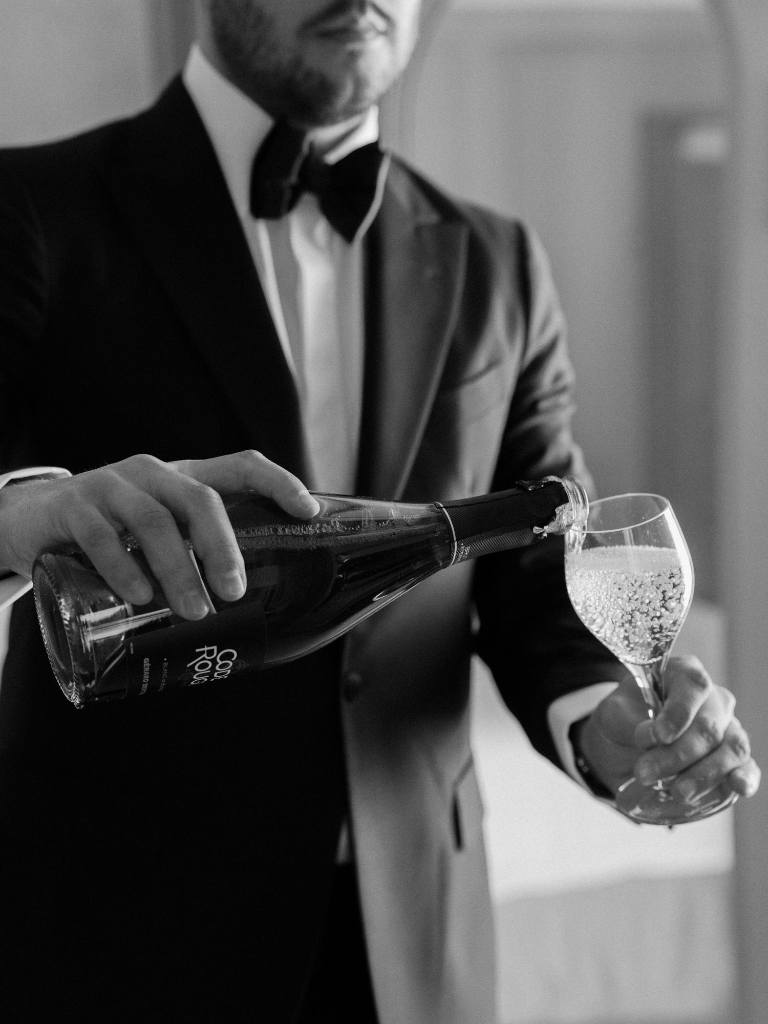 Champagne being poured into a glass by someone wearing a formal suit.