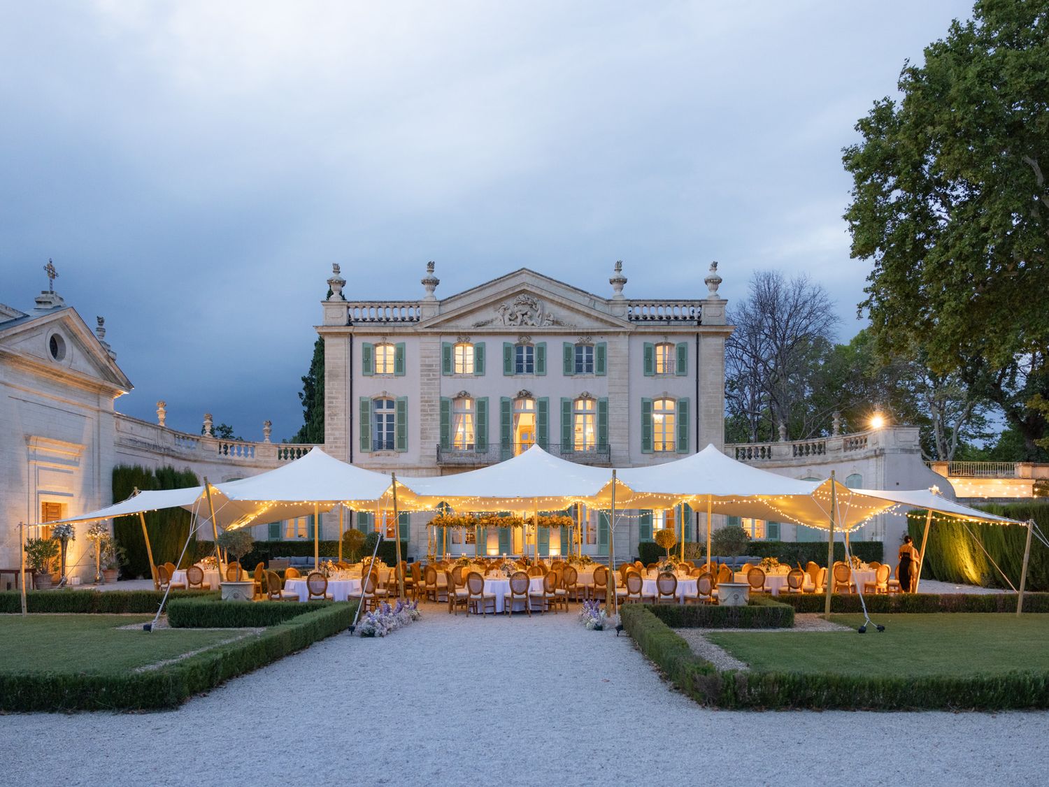 Elegant mansion venue at dusk with outdoor tent reception and warm lighting creating a romantic atmosphere.
