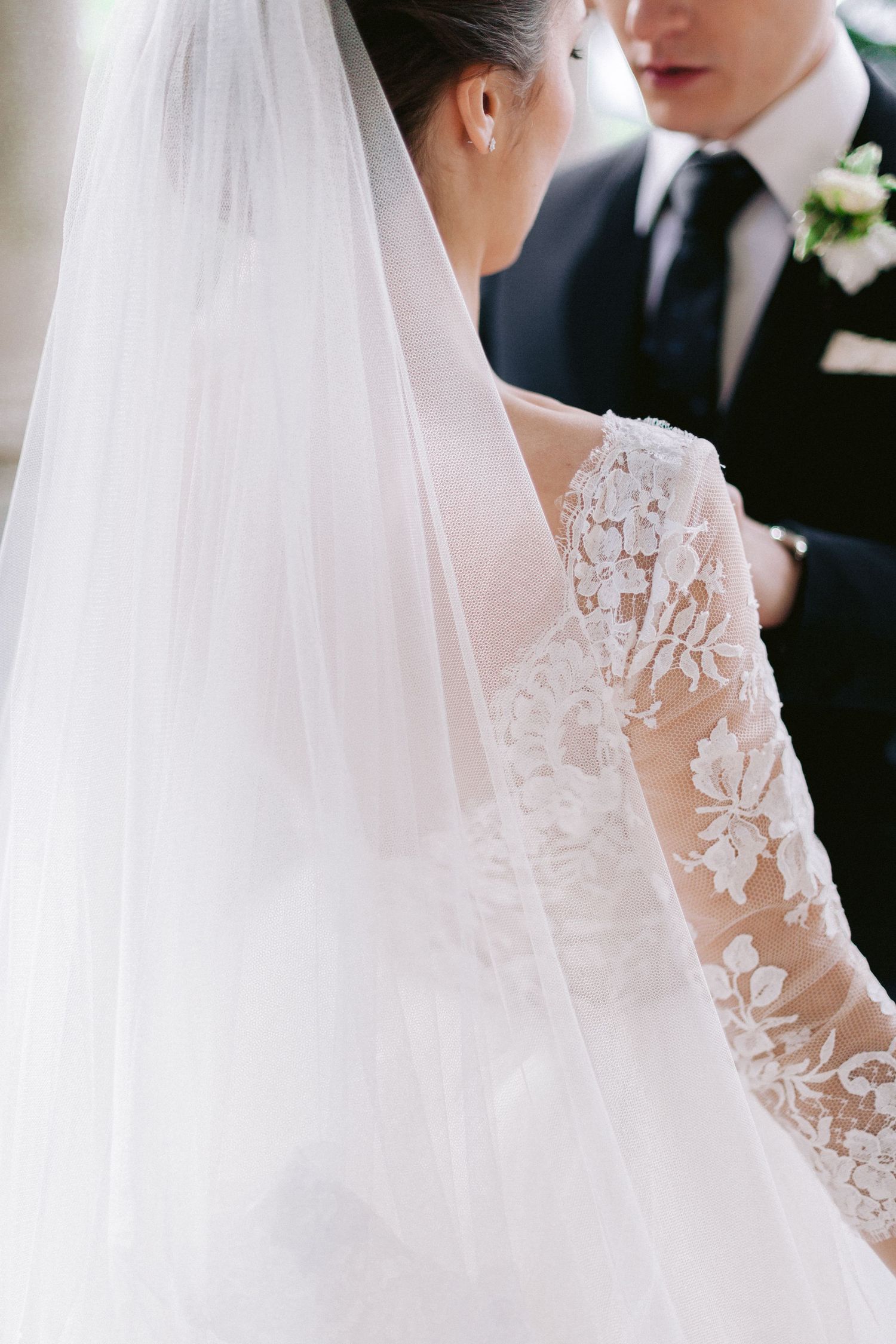 Close-up of intricate lace detailing on a wedding dress with sheer veil.