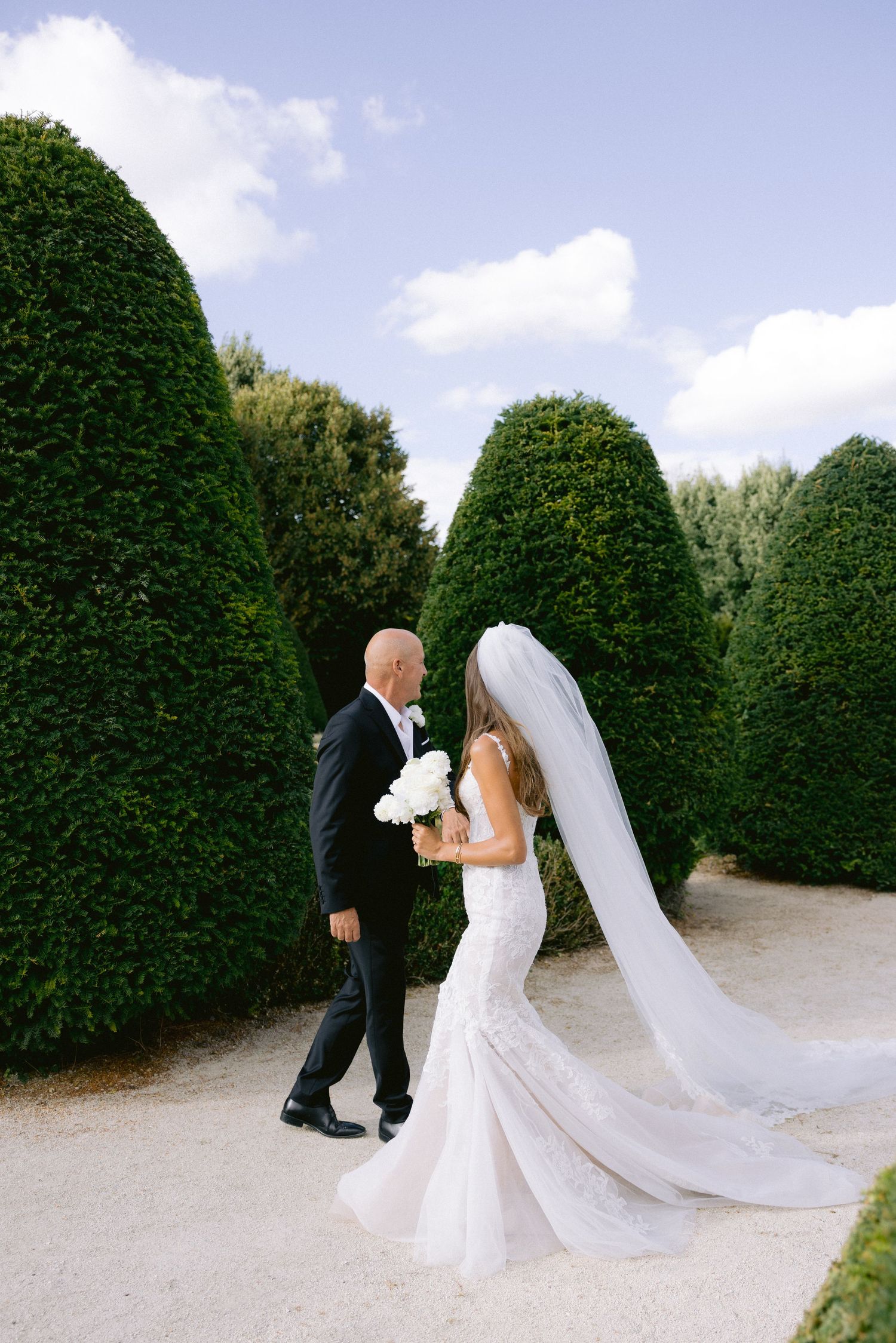 Château de Sept Saulx Romantic wedding portrait among manicured garden hedges with flowing veil.