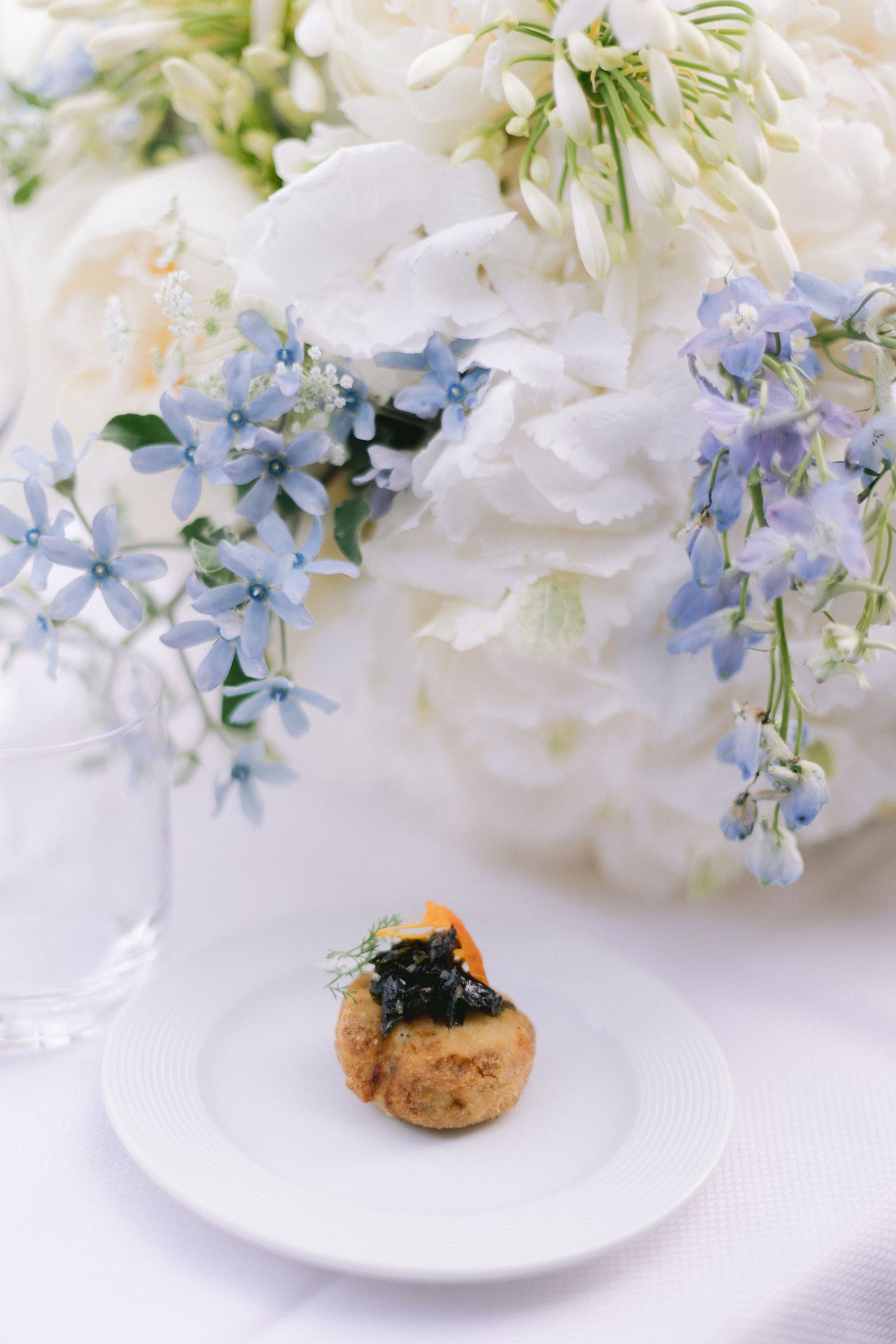 Delicate white and blue floral arrangements displayed on white plates.