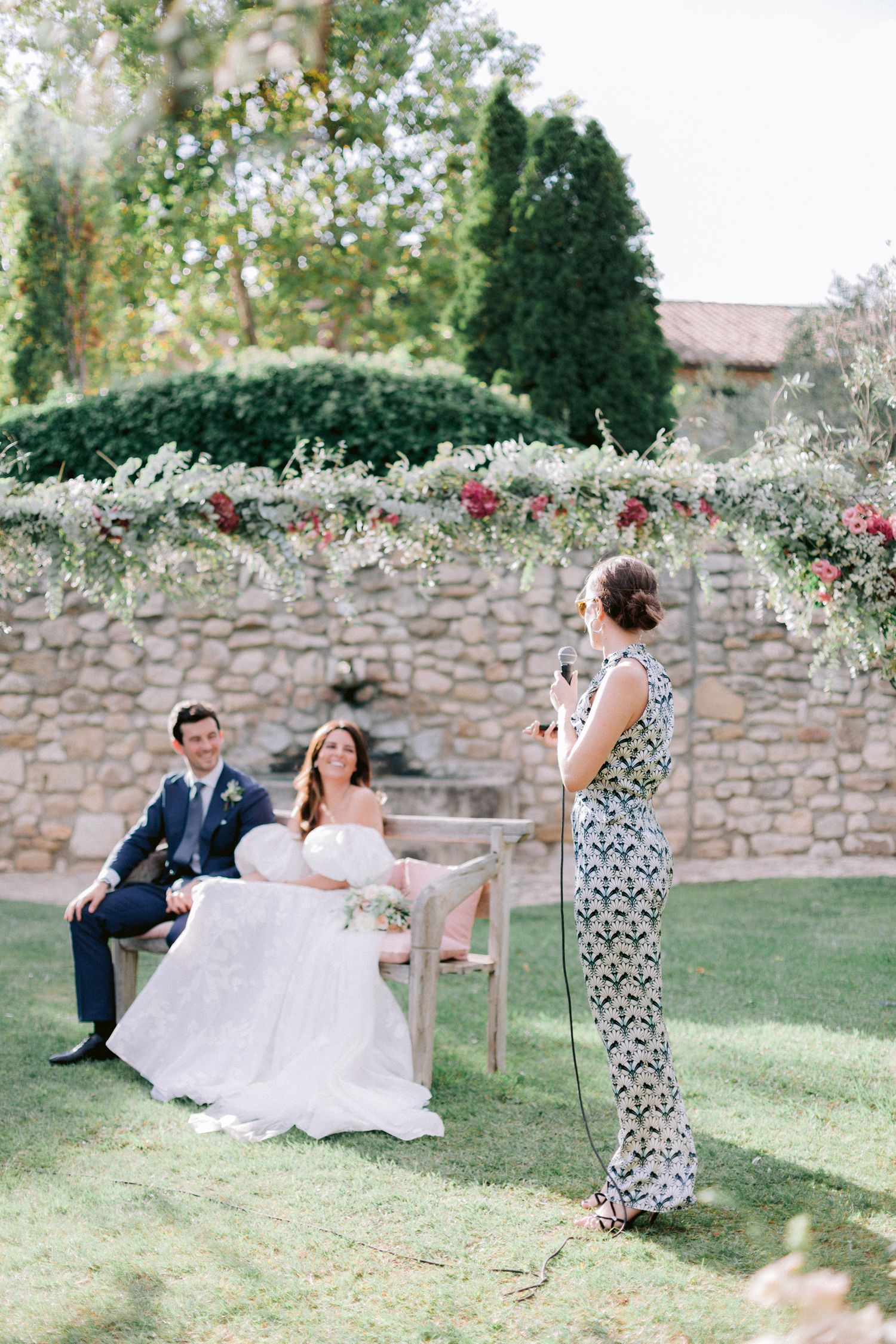 Wedding photography session in a garden setting with stone wall backdrop.