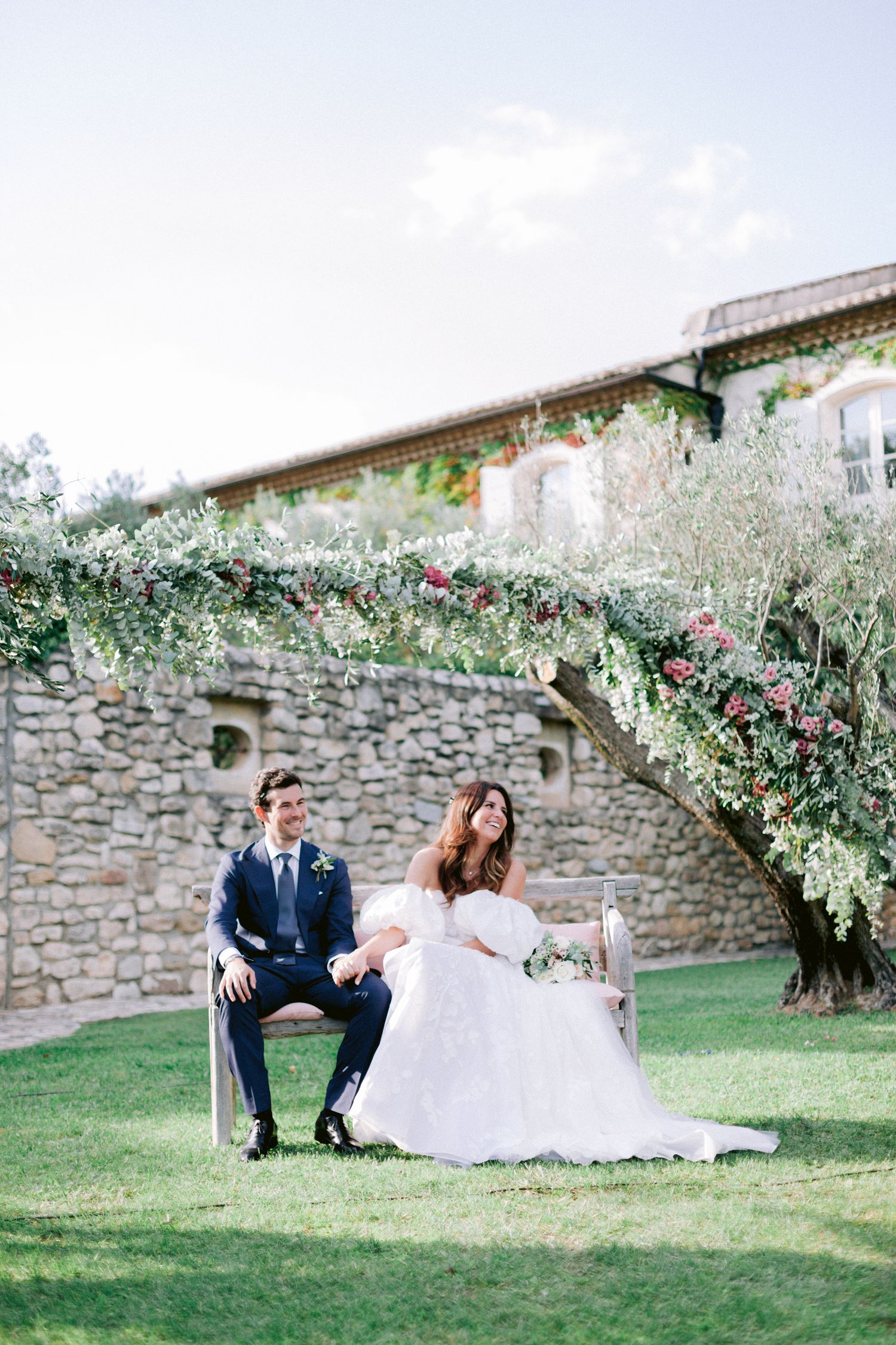 Romantic wedding photo session in front of a rustic stone wall with lush greenery.