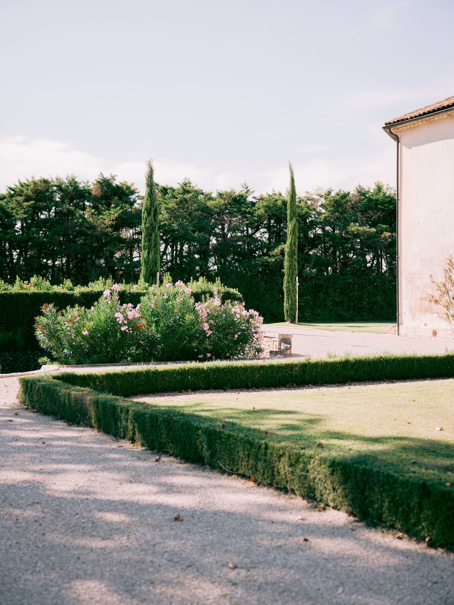 Manicured garden pathway with cypress trees and hedges at an upscale venue.
