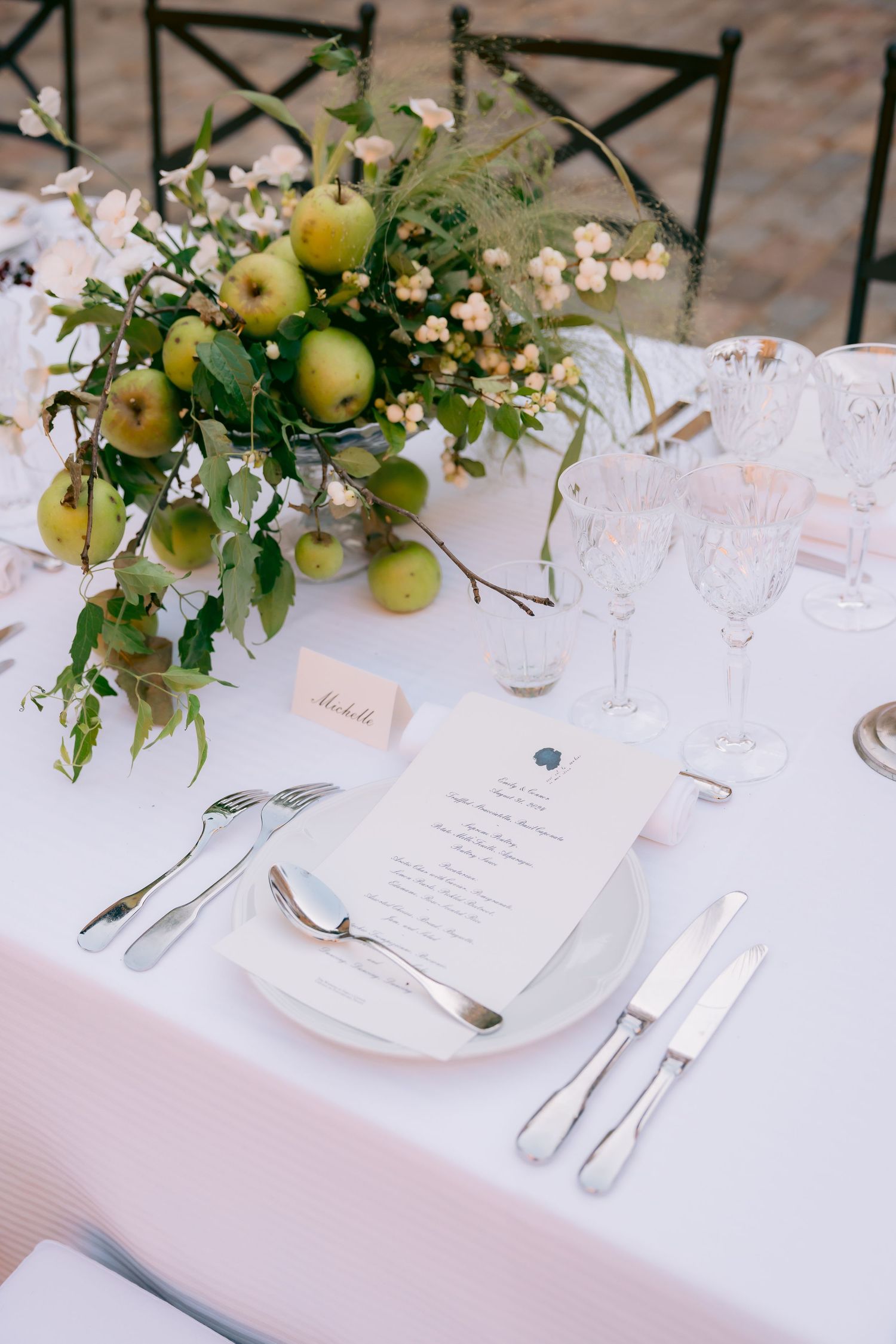 Elegant wedding table setting with white linens, place cards and floral centerpieces.