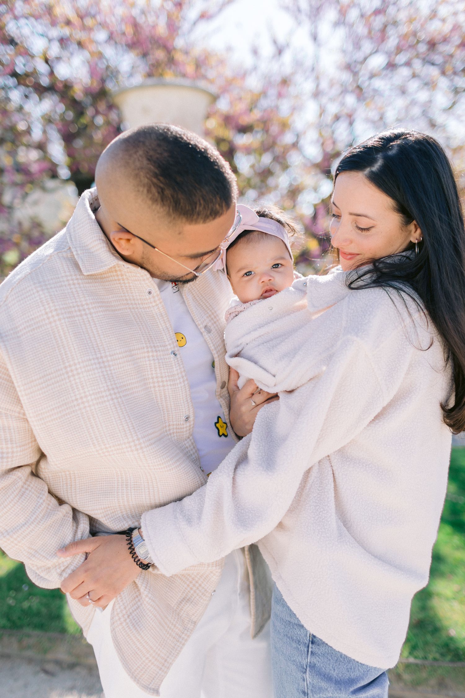 Family sharing tender moments together outdoors wearing coordinating white outfits.