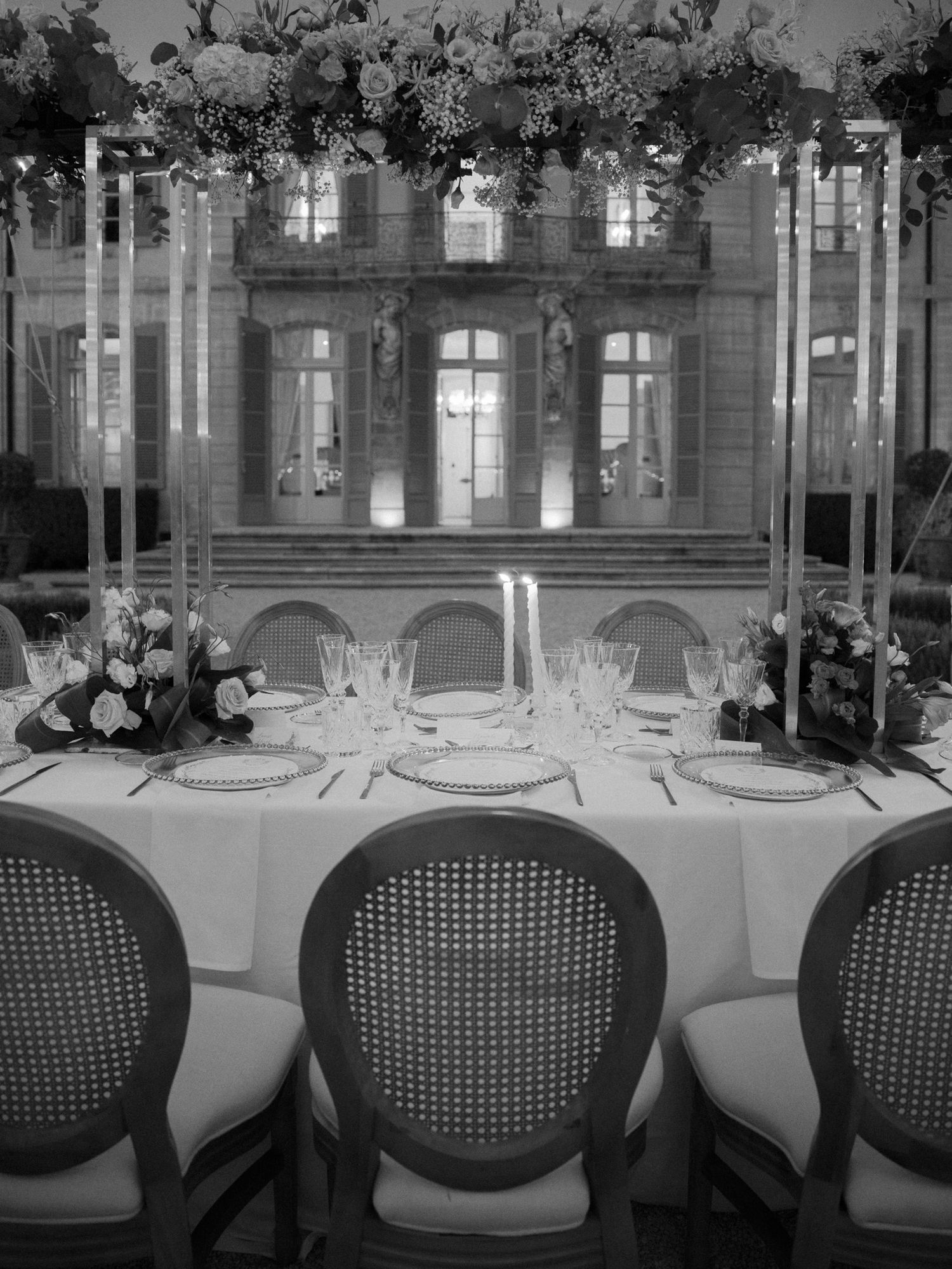 Formal dining room setup with cane-back chairs and white tablecloths in an elegant venue.