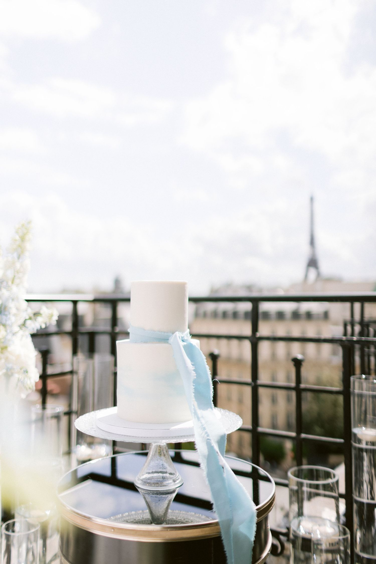 Wedding cake and table settings arranged on a rooftop terrace with decorative elements.