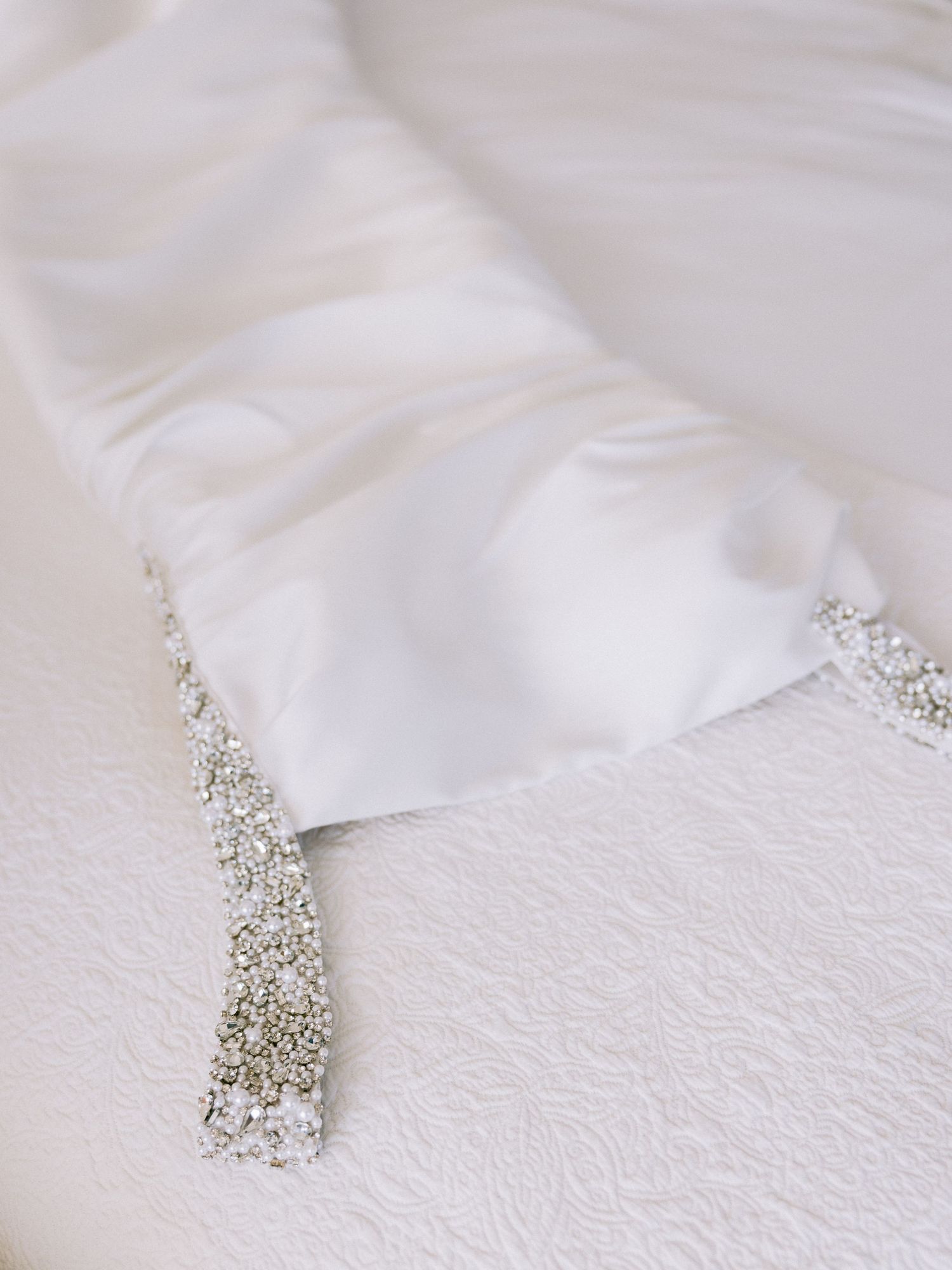 Delicate crystal bridal hair accessory on white textured fabric.