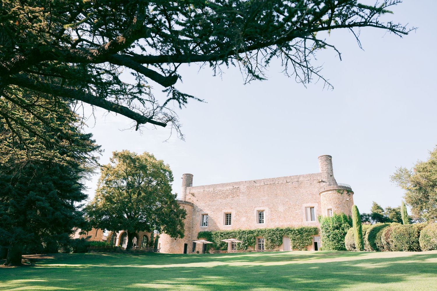 Panoramic view of a historic stone mansion with manicured grounds and trees.