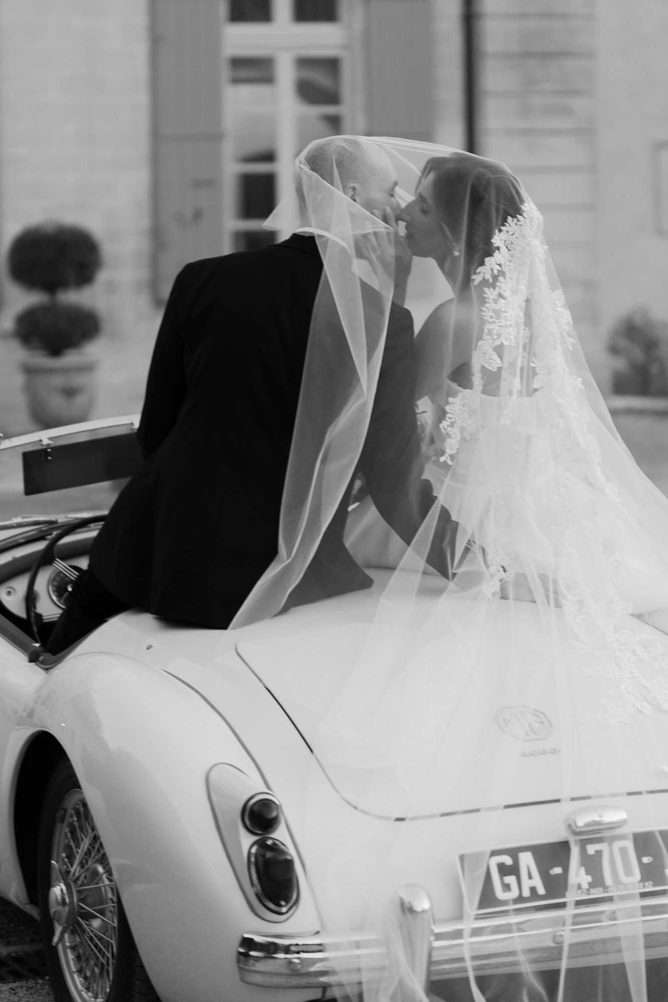 A black and white photo of a classic MG sports car decorated for a wedding.