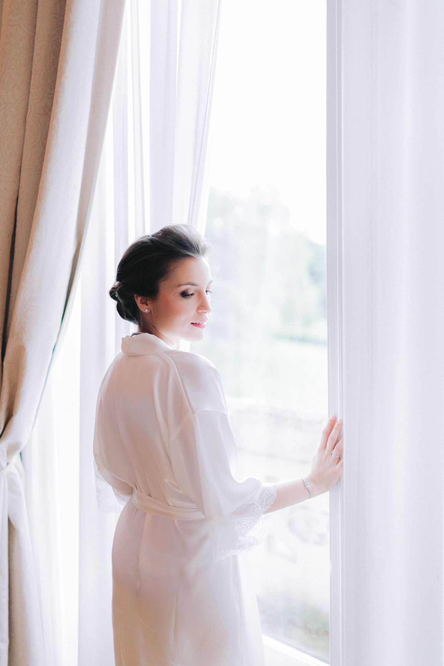Ethereal morning light streams through sheer curtains in a bridal preparation room.