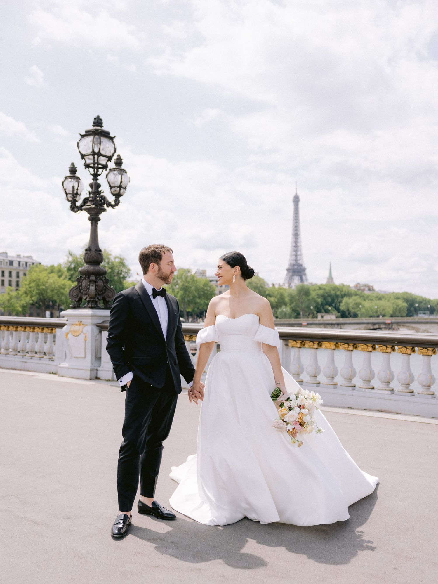Romantic wedding portrait on Paris bridge with Eiffel Tower in background.