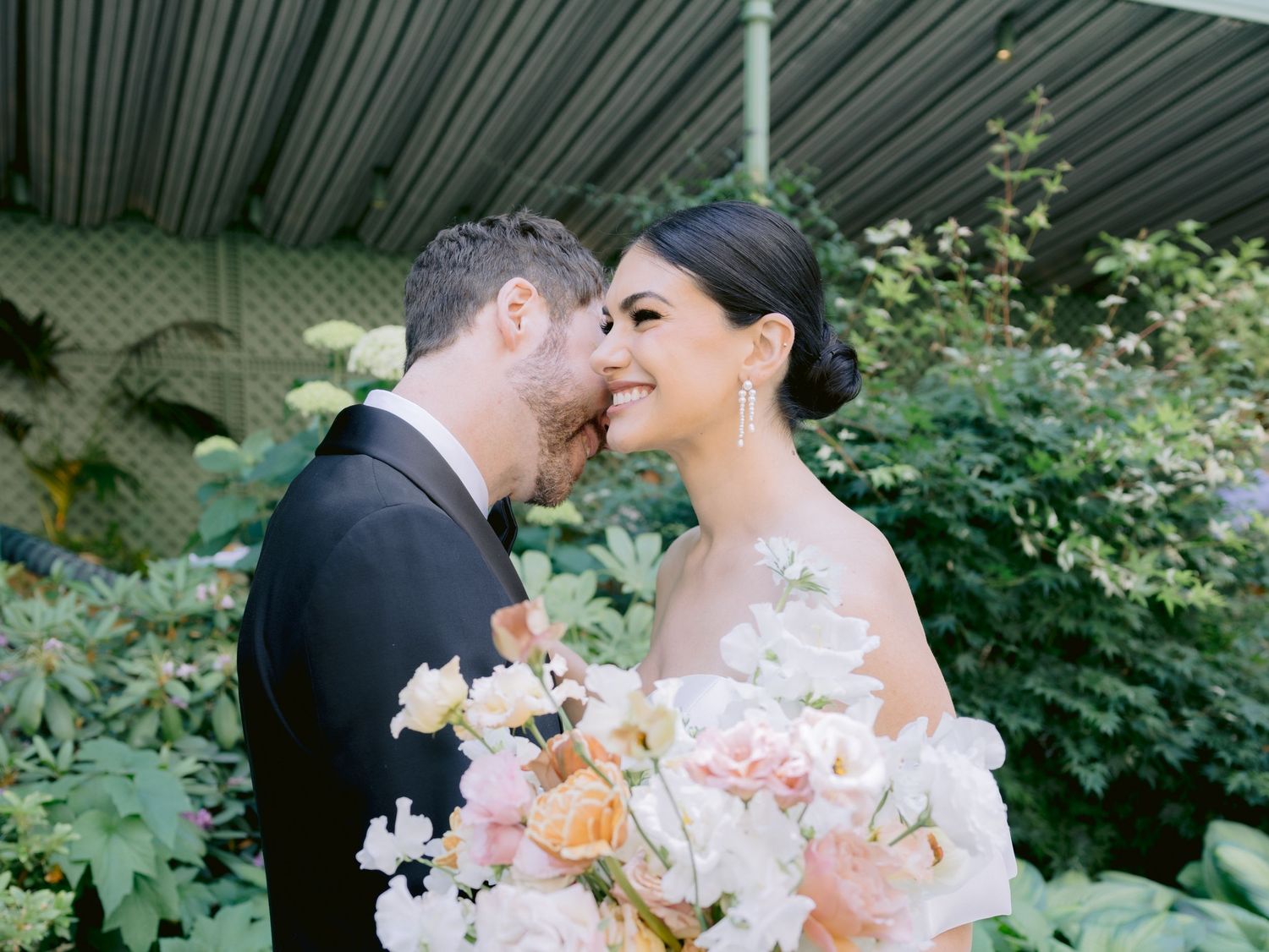 A romantic couple shares tender moments in a garden setting with pink and white floral bouquets.