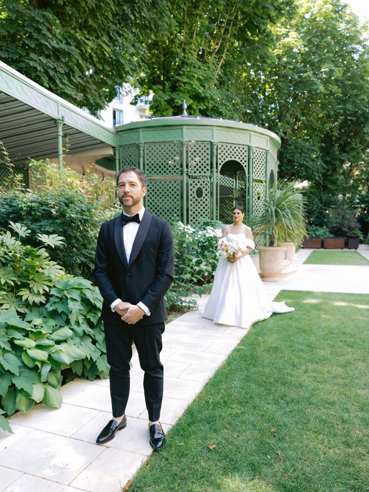 First look moment captured in garden setting with lattice pergola and stone pathway.