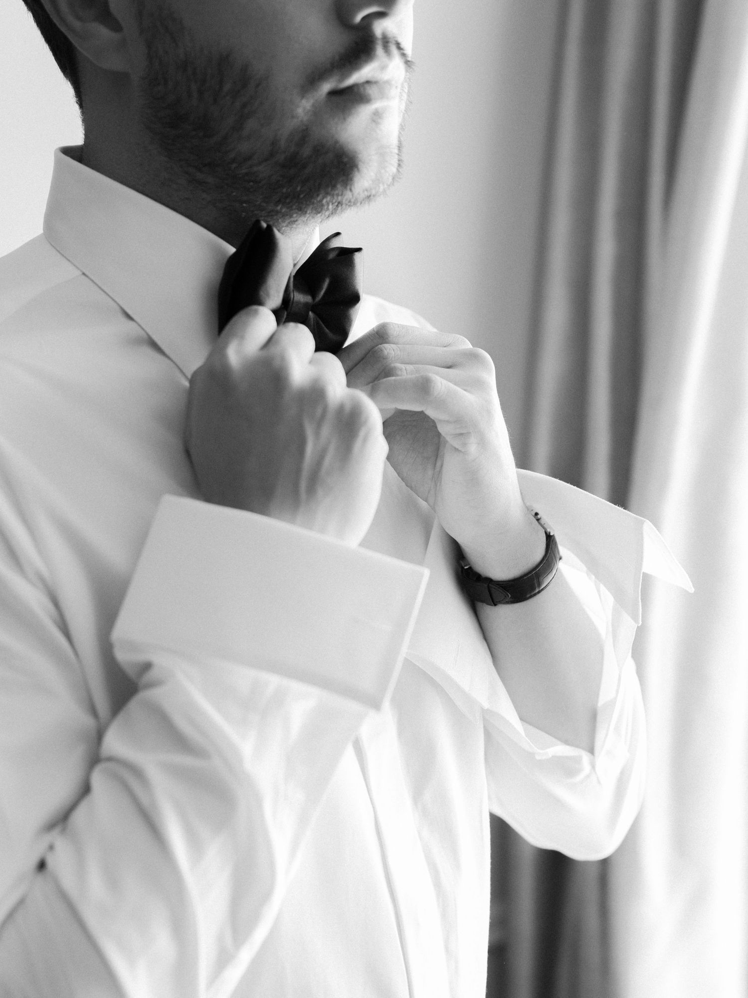 Close-up of formal white shirt collar and tie being adjusted.