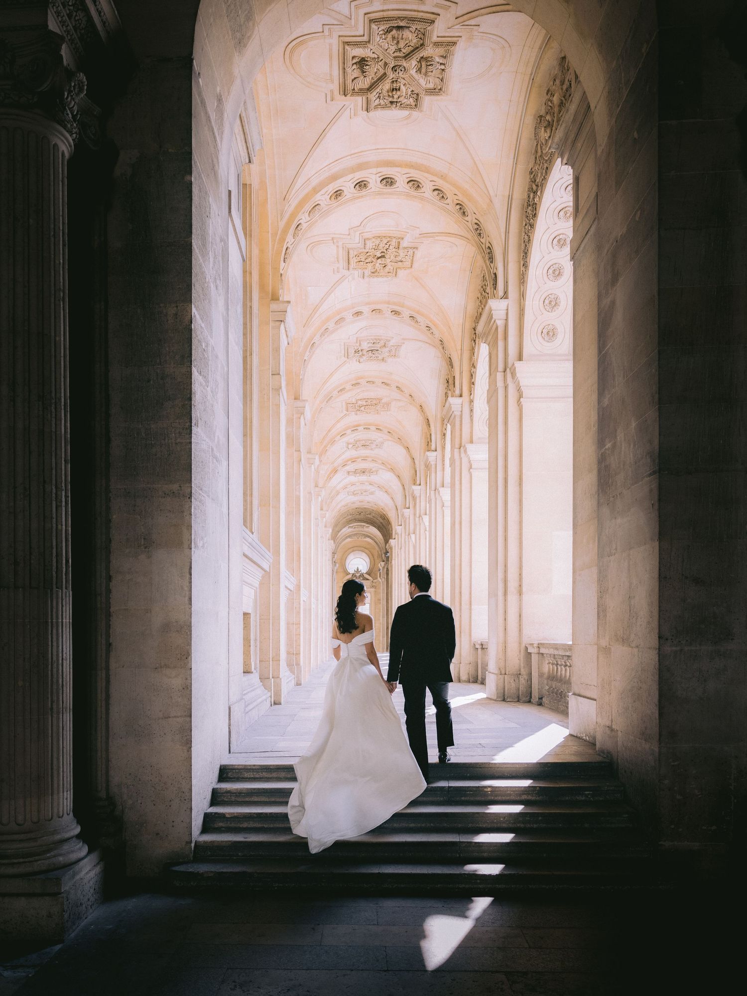 Dramatic archways frame a wedding couple in an elegant classical corridor.