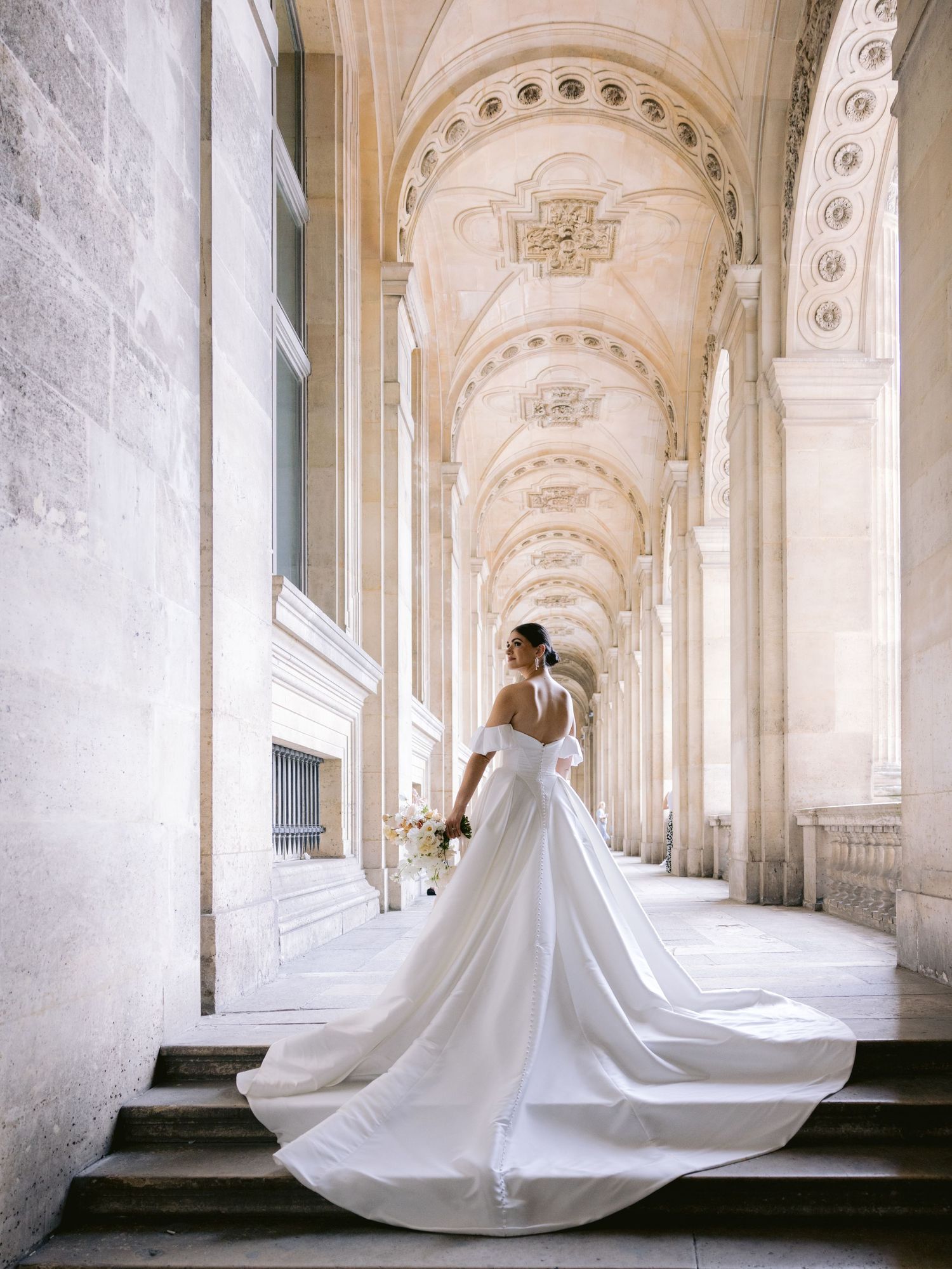 Classic wedding dress with cathedral train photographed in grand columned hallway.