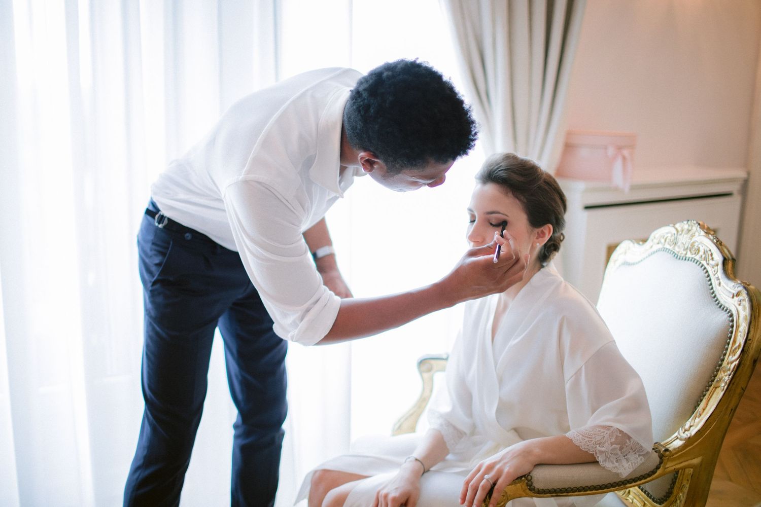 A touching moment during wedding preparations in an elegant white room.