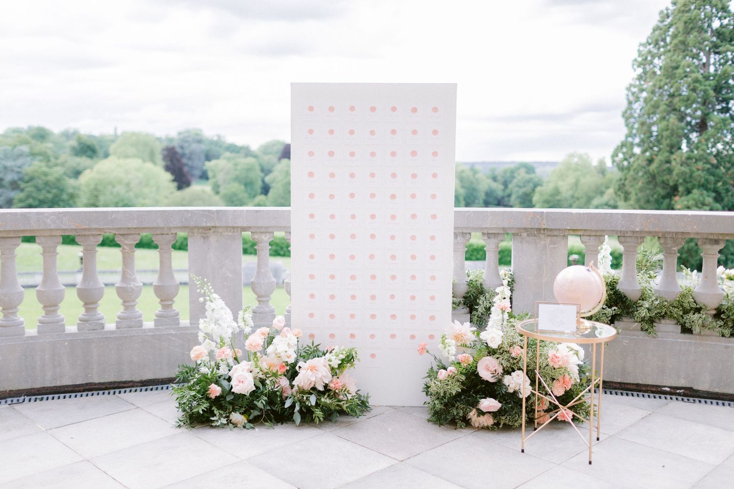 White wedding floral arrangements line a pathway in an outdoor garden setting.