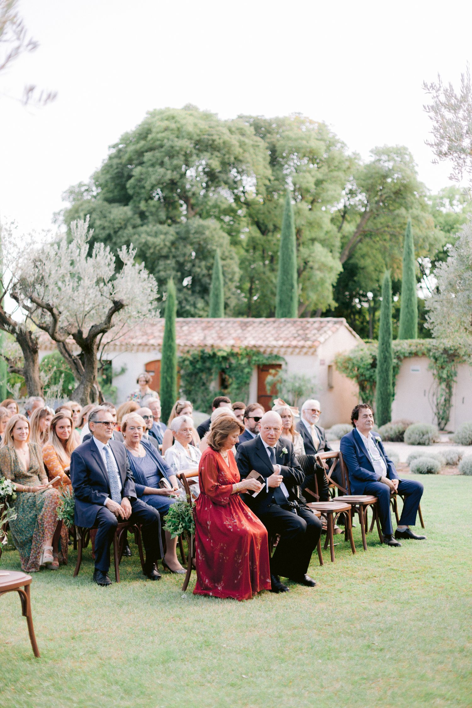 Wedding guests seated on wooden chairs during an outdoor ceremony with desert landscaping and cacti.