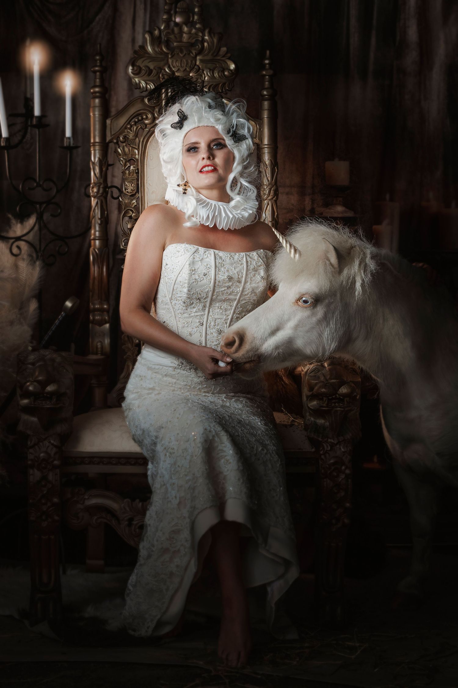 A dramatic Victorian-style portrait featuring someone in a white dress posed on an ornate throne with a white pony.