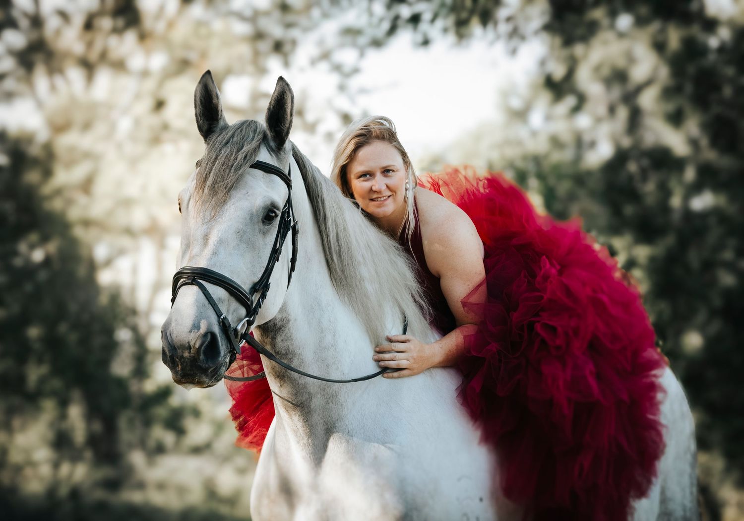 Portrait featuring a white horse with someone in a dramatic red tulle dress.