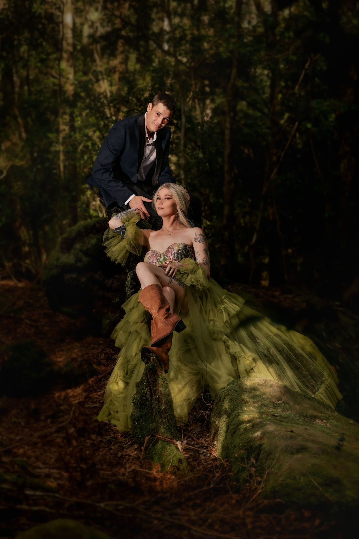 Romantic forest photoshoot with couple in formal wear featuring dramatic green gown.