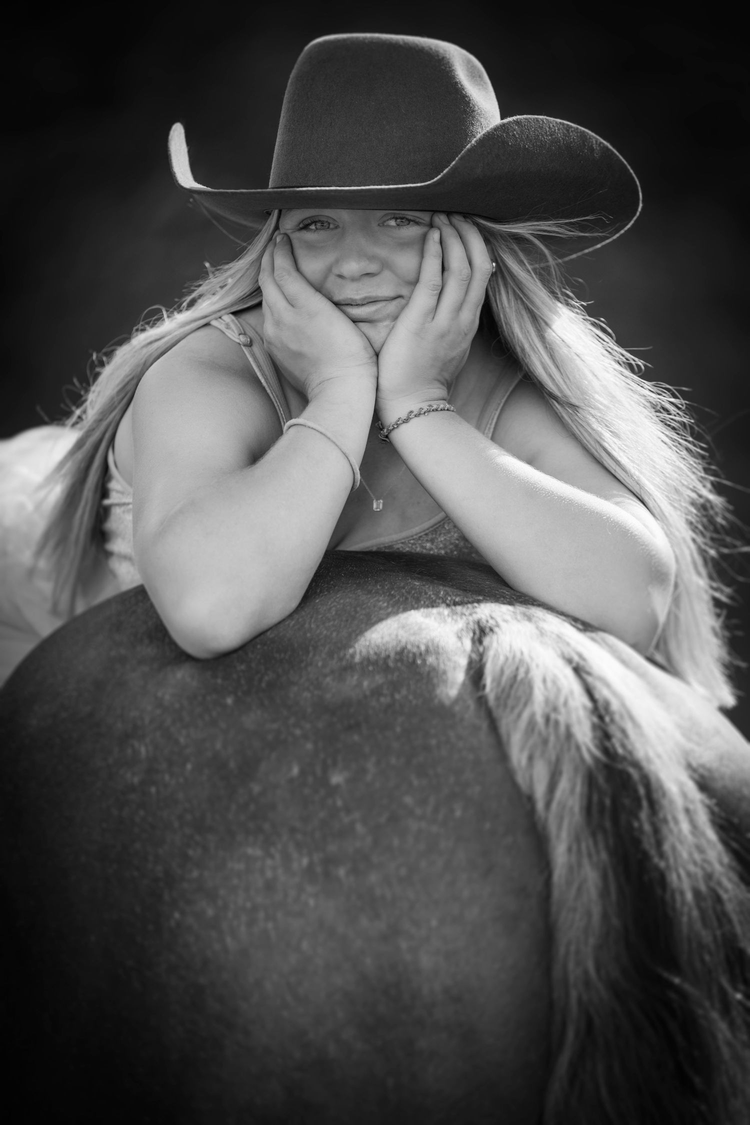 Artistic black and white equestrian portrait with cowboy hat and horse.