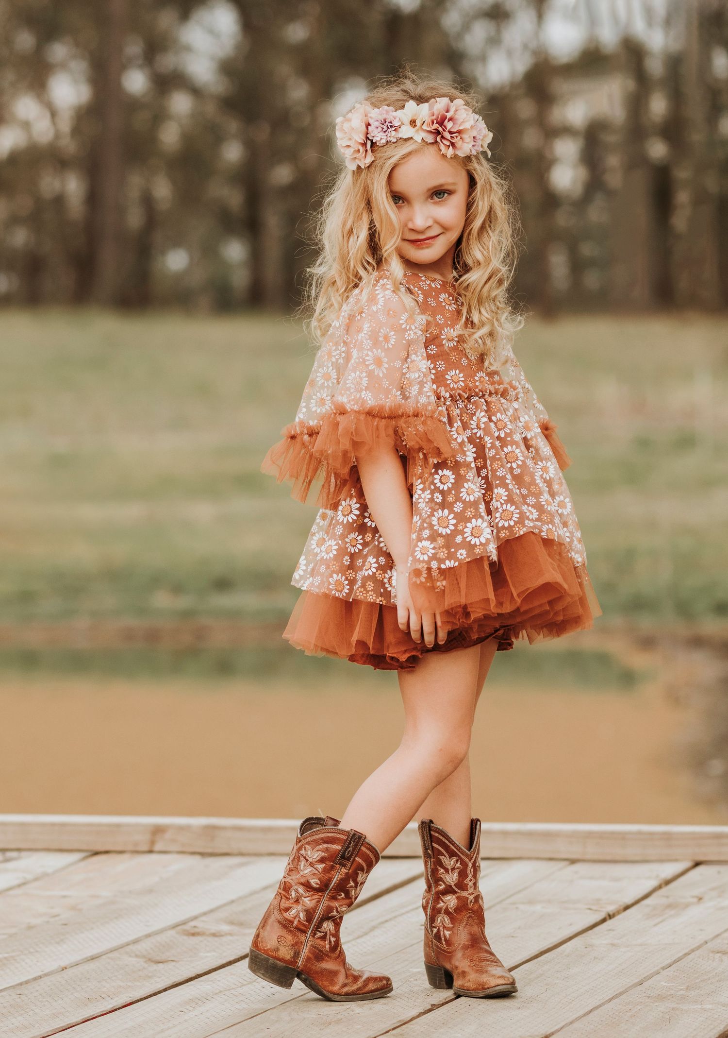 Whimsical peach lace dress with tulle layers paired with brown cowboy boots for country-chic style.