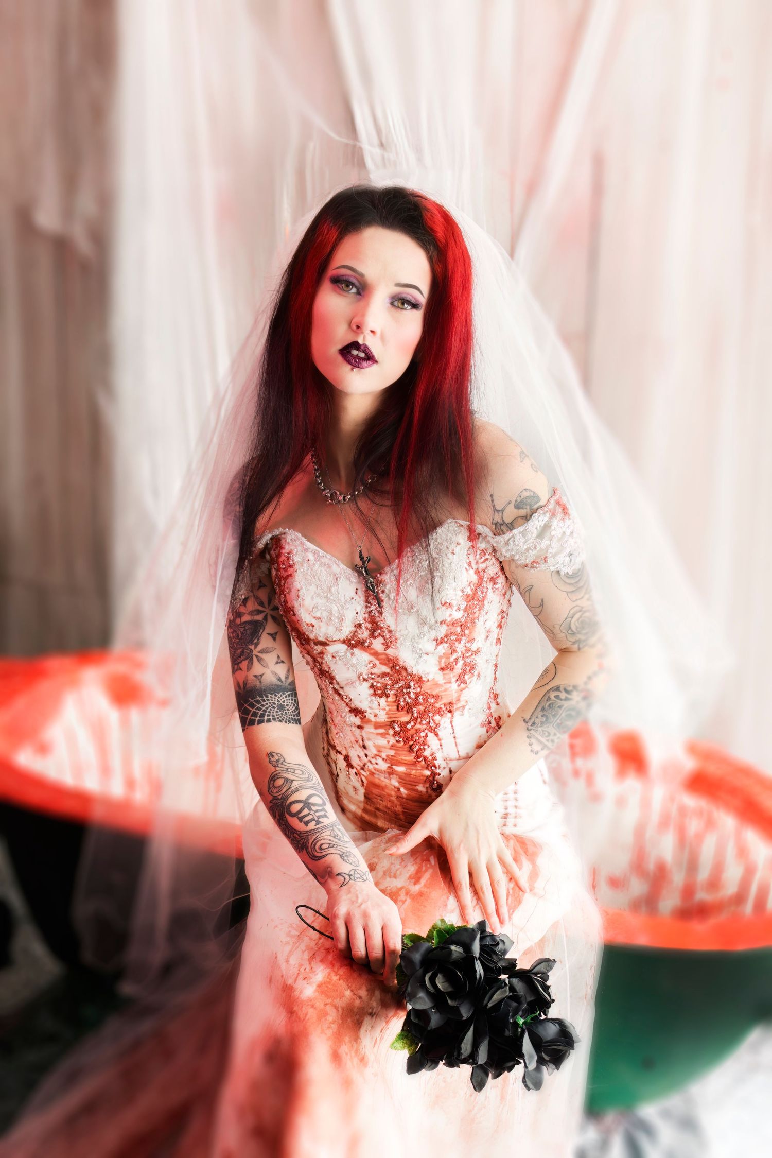 Alternative bridal portrait with red hair and tattoos against pink and coral backdrop.