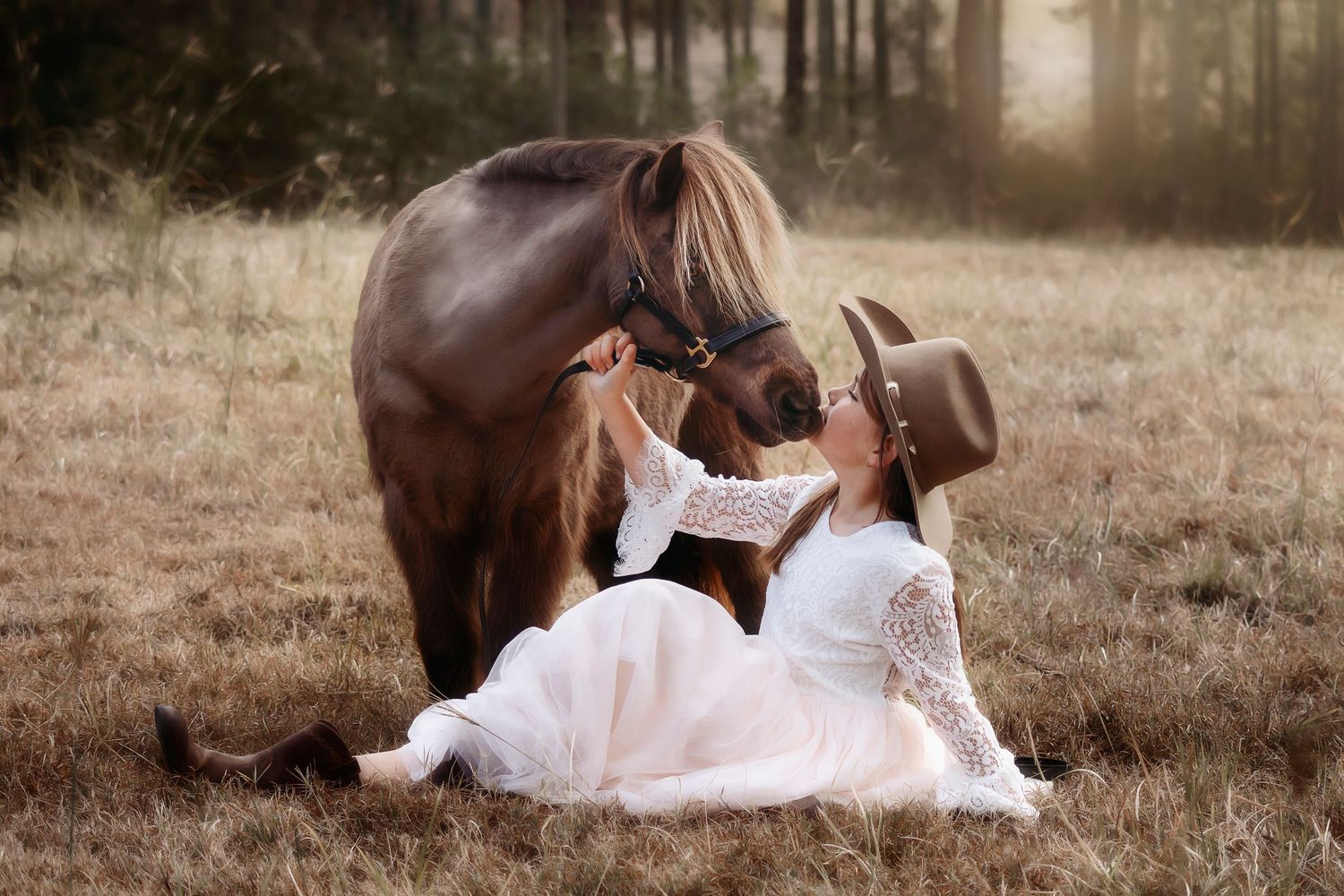 A tender moment between a brown horse and someone in a white dress and cowboy hat.