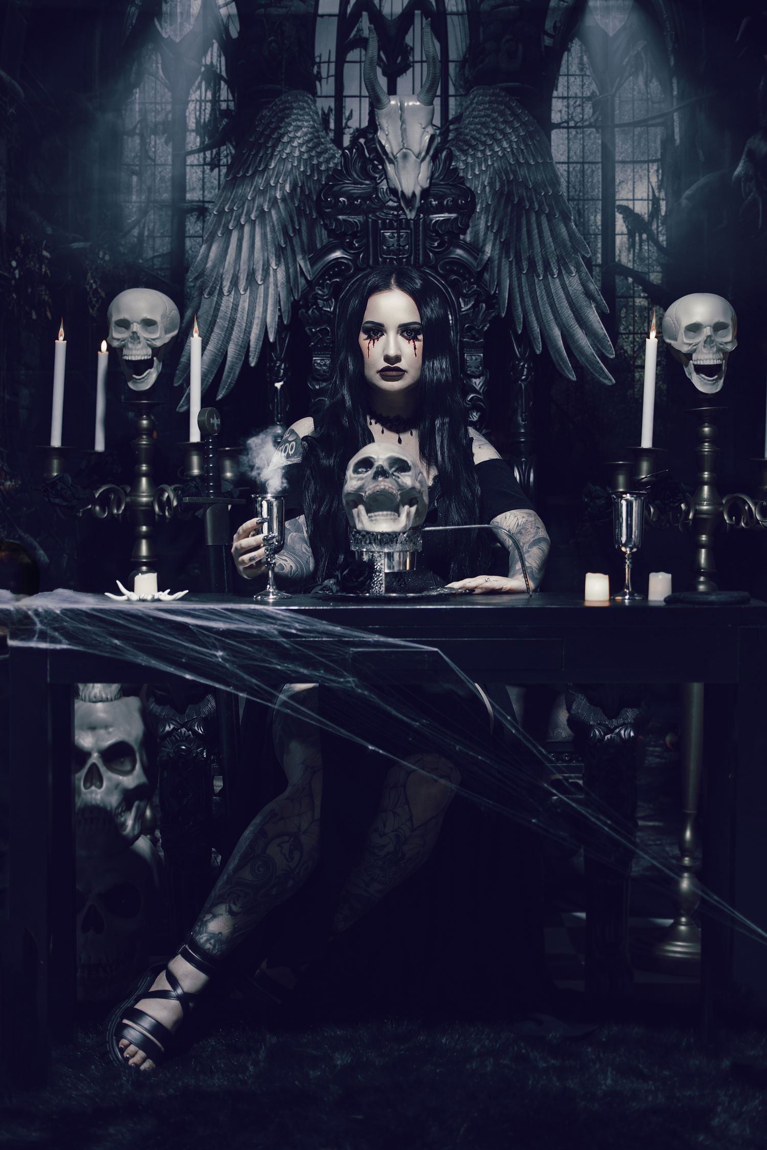 Dark gothic scene with winged figure, skulls and candles creating a moody atmospheric composition.