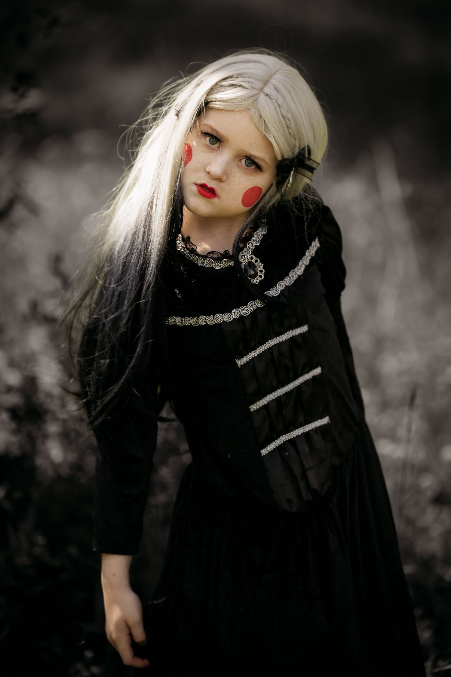 Gothic-inspired fashion portrait with black and white styling, silver accents, and dramatic red makeup against dark background.