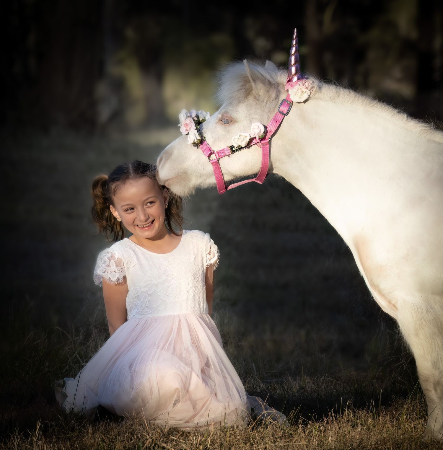 A magical moment with a white pony wearing a unicorn horn and pink floral decorations.