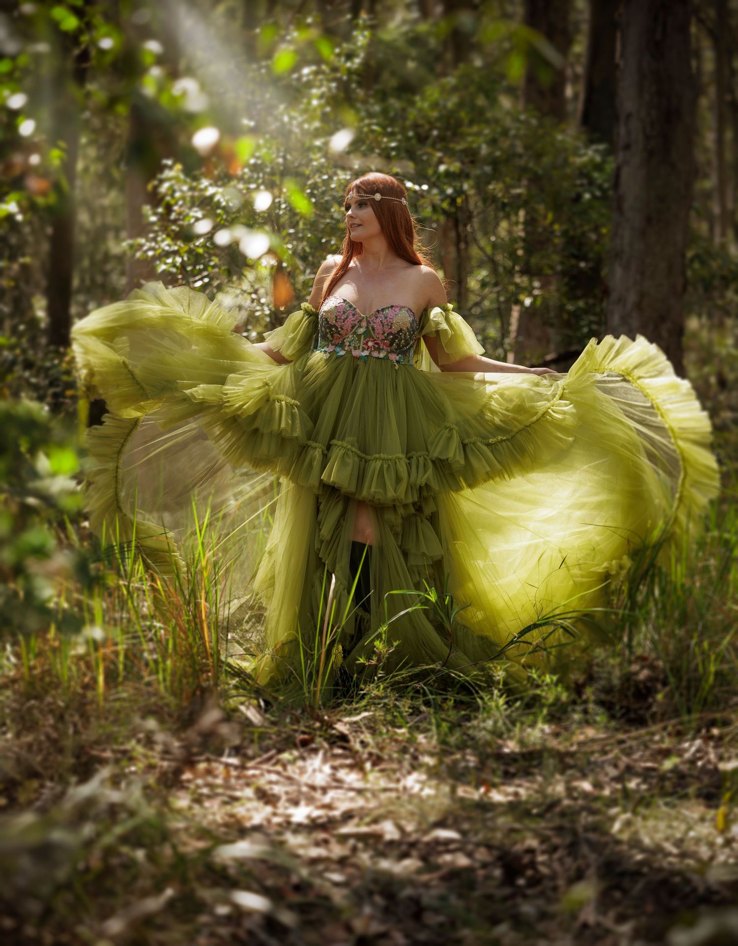 A flowing chartreuse gown with ruffled tulle fabric creates an ethereal scene in a sunlit wooded forest setting.