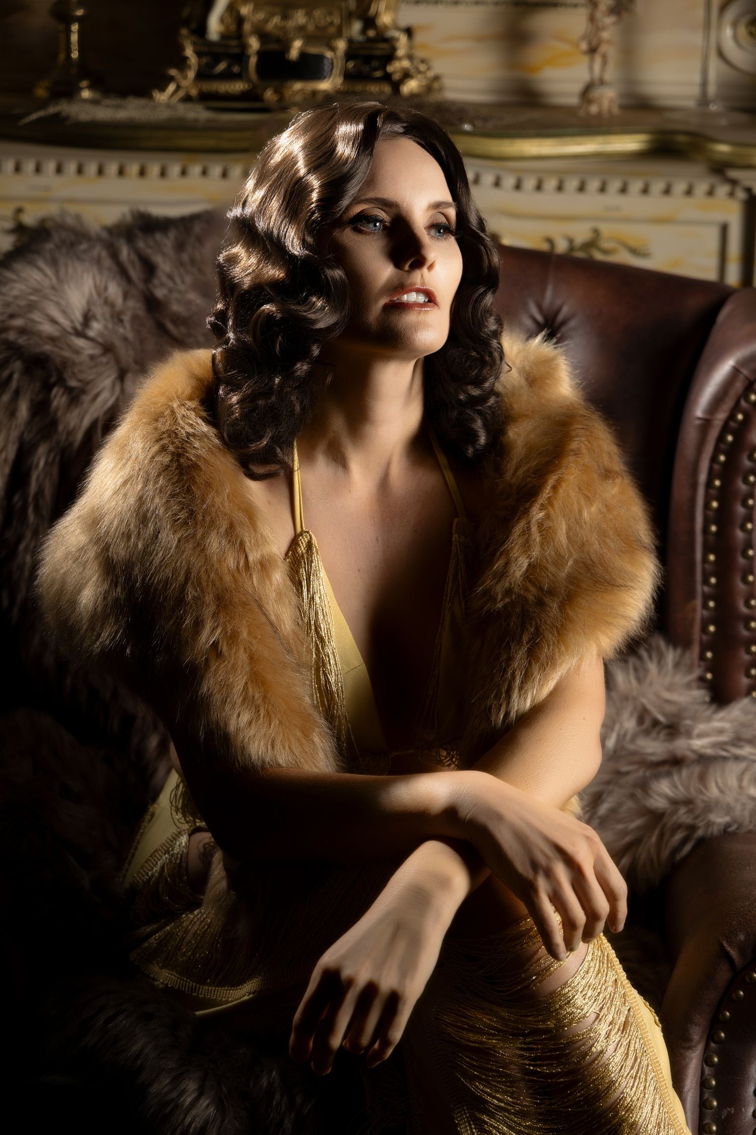 Glamorous vintage-inspired portrait with gold sequin dress and fur stole in luxurious interior setting.